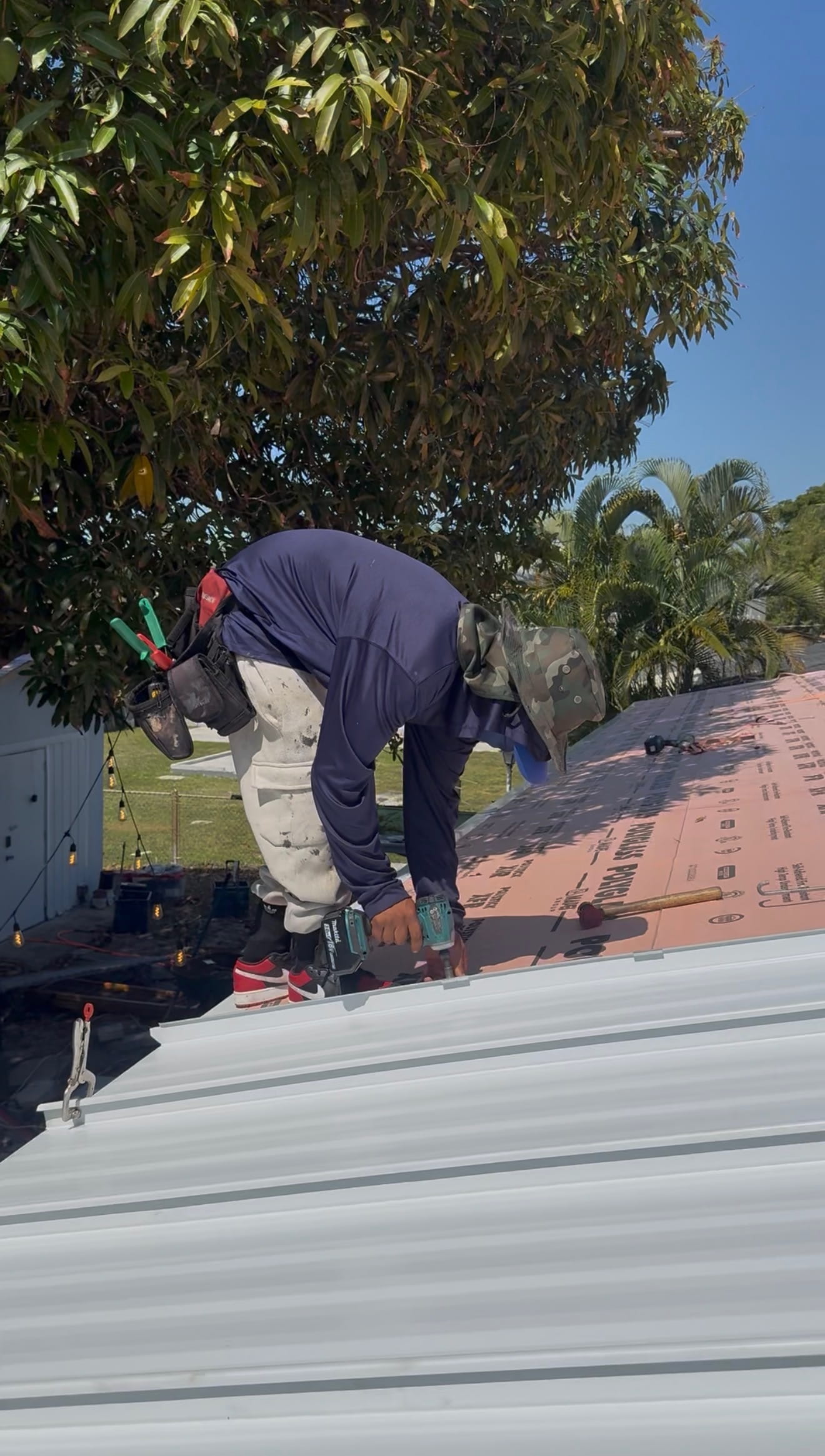 Metal roofing installation in progress with worker installing panels.