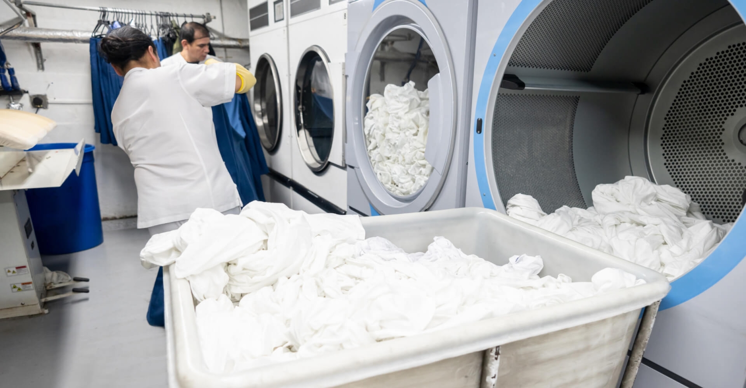Lavandería industrial con trabajadores procesando ropa blanca