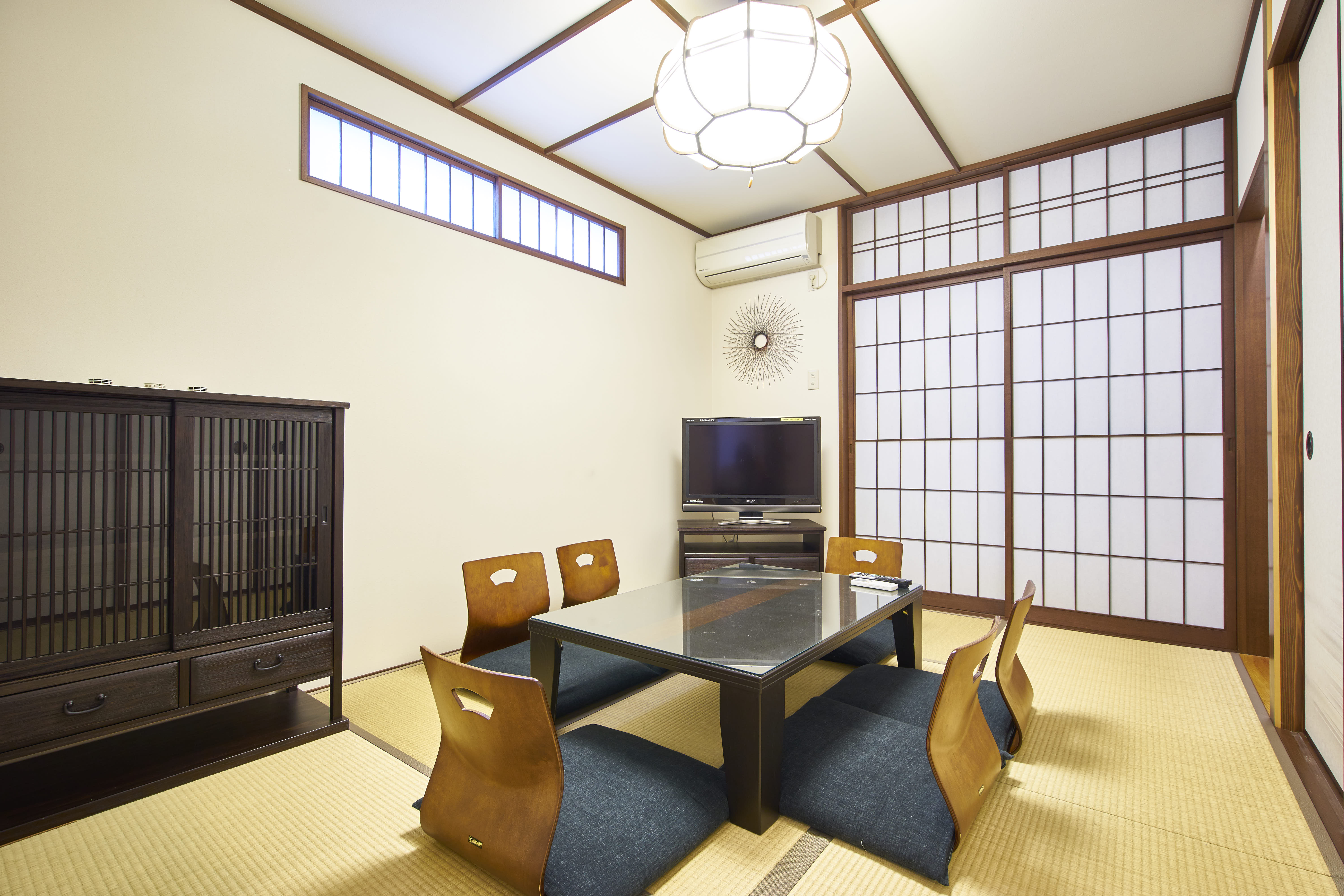 Traditional tatami dining room with low lacquered table, floor chairs, shoji screens, and antique tansu cabinet