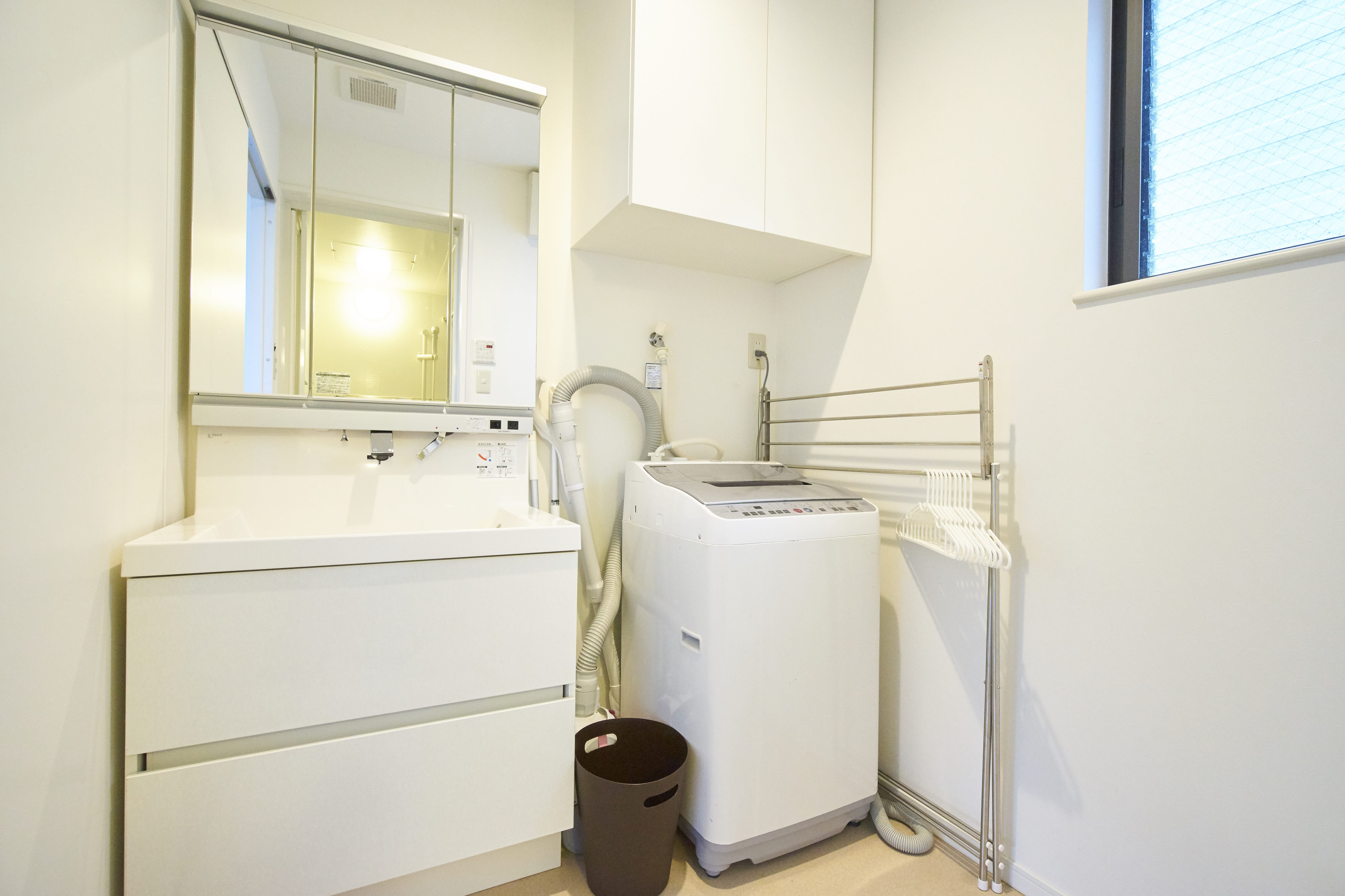 Utility room with large vanity mirror, washing machine, and drying rack