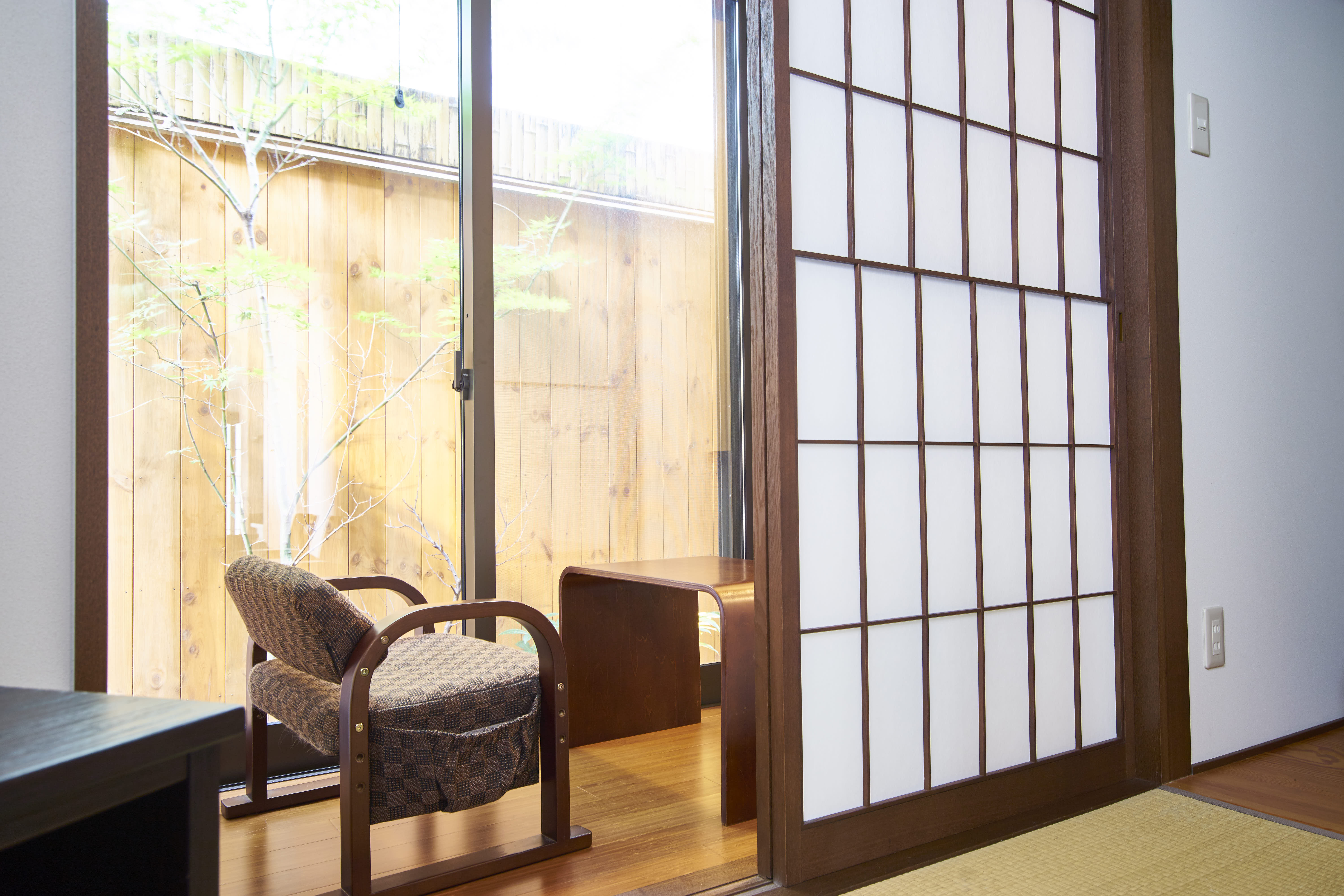 Serene garden view from tatami room with shoji screens, low chair, and private wooden deck