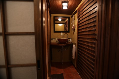 Warm corridor with woven bamboo ceiling, ceramic vessel sink, and atmospheric lantern lighting
