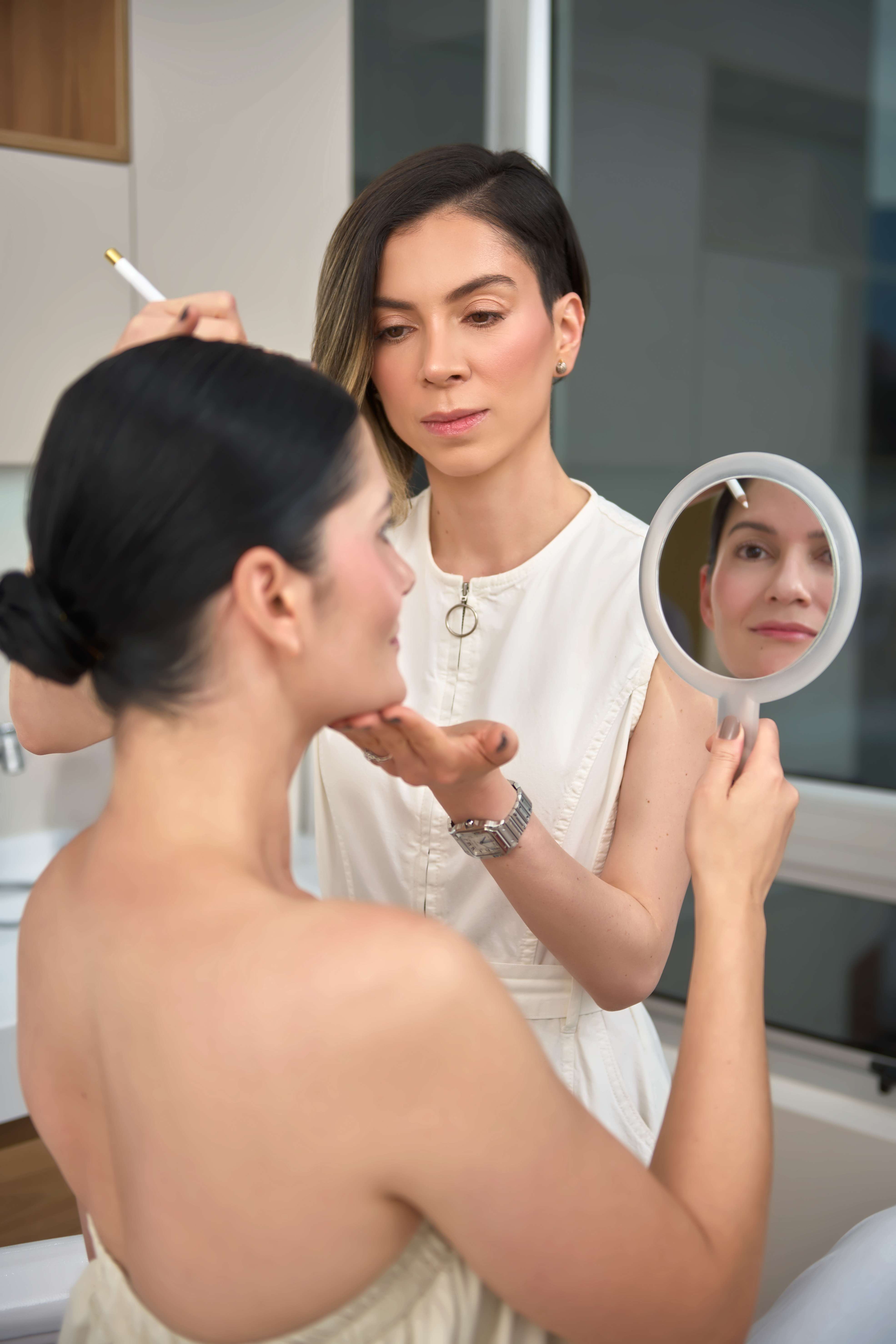 Especialista de Clínica Ohmio realizando valoración facial con espejo de mano a paciente