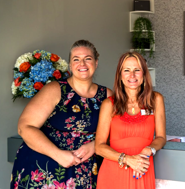 The two Prime IV Flemington owners smiling together by a floral arrangement