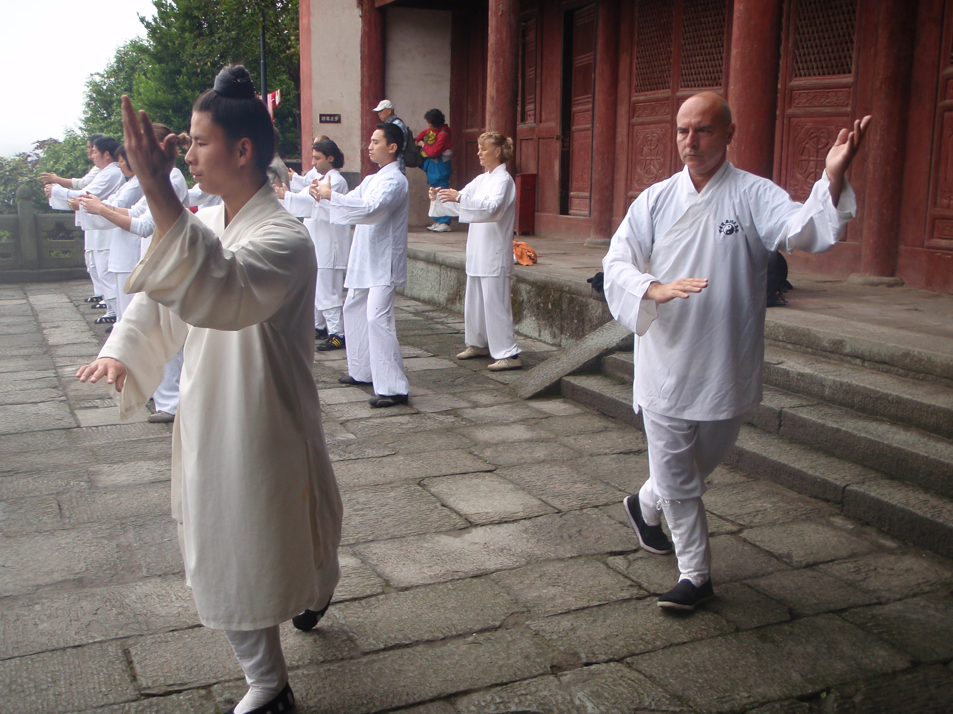 Misty morning synchronized practice on stone temple terrace, female master in beige leading rows of students in white