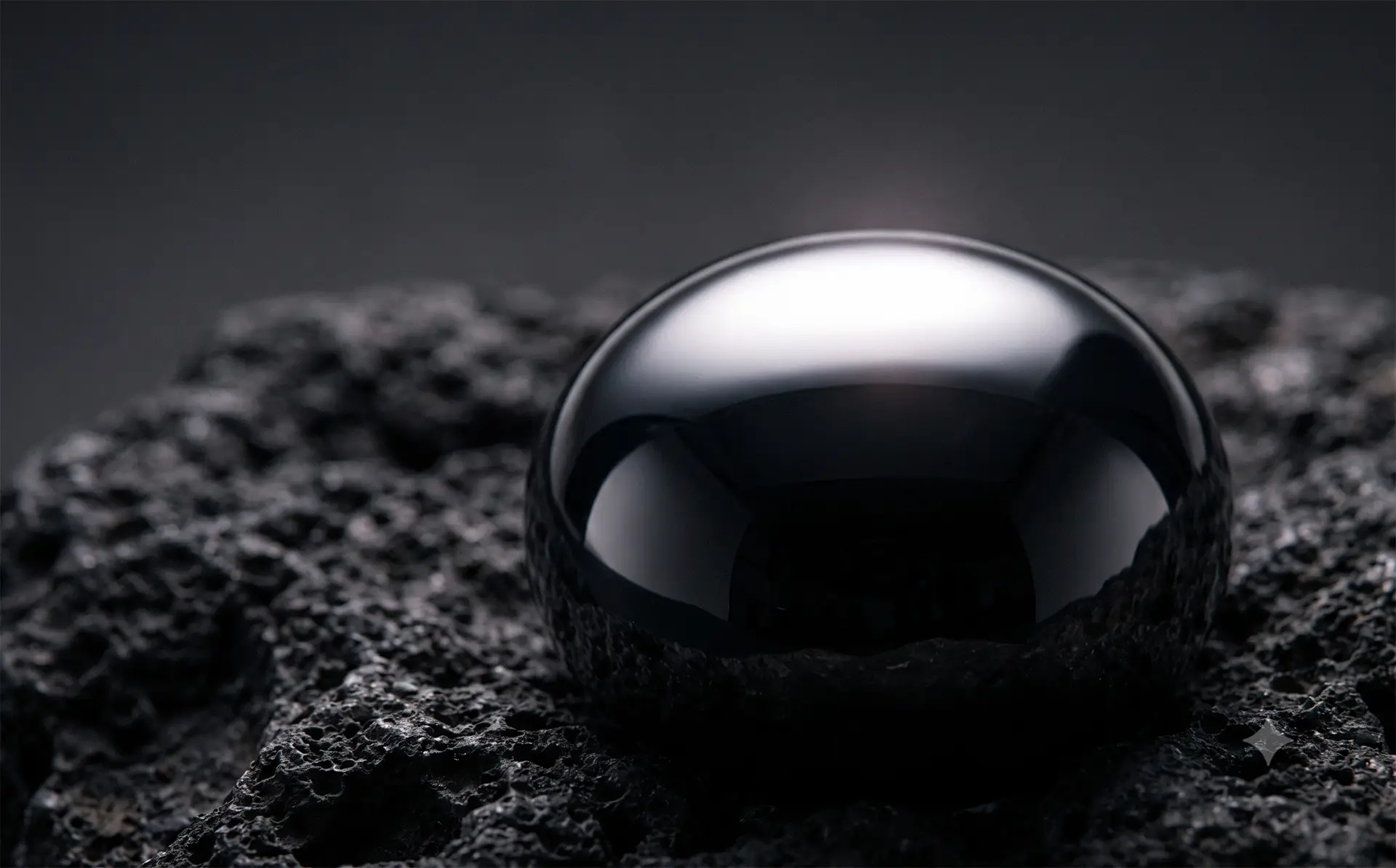 Black obsidian sphere on dark rock — Skin & Radiance