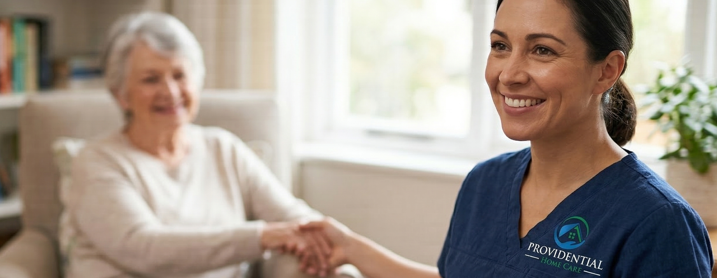 Smiling Providential Home Care caregiver in branded scrubs providing compassionate care to a senior client in a bright, welcoming home