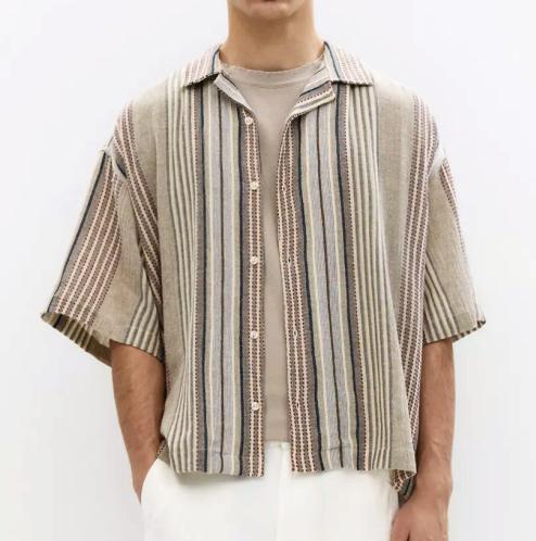 Model wearing a relaxed short-sleeve shirt with muted vertical stripes.