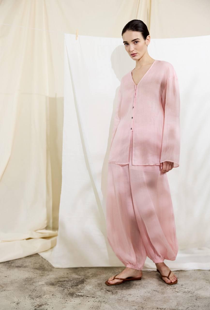 Model wearing a soft pink button-front shirt and matching wide-leg trousers.