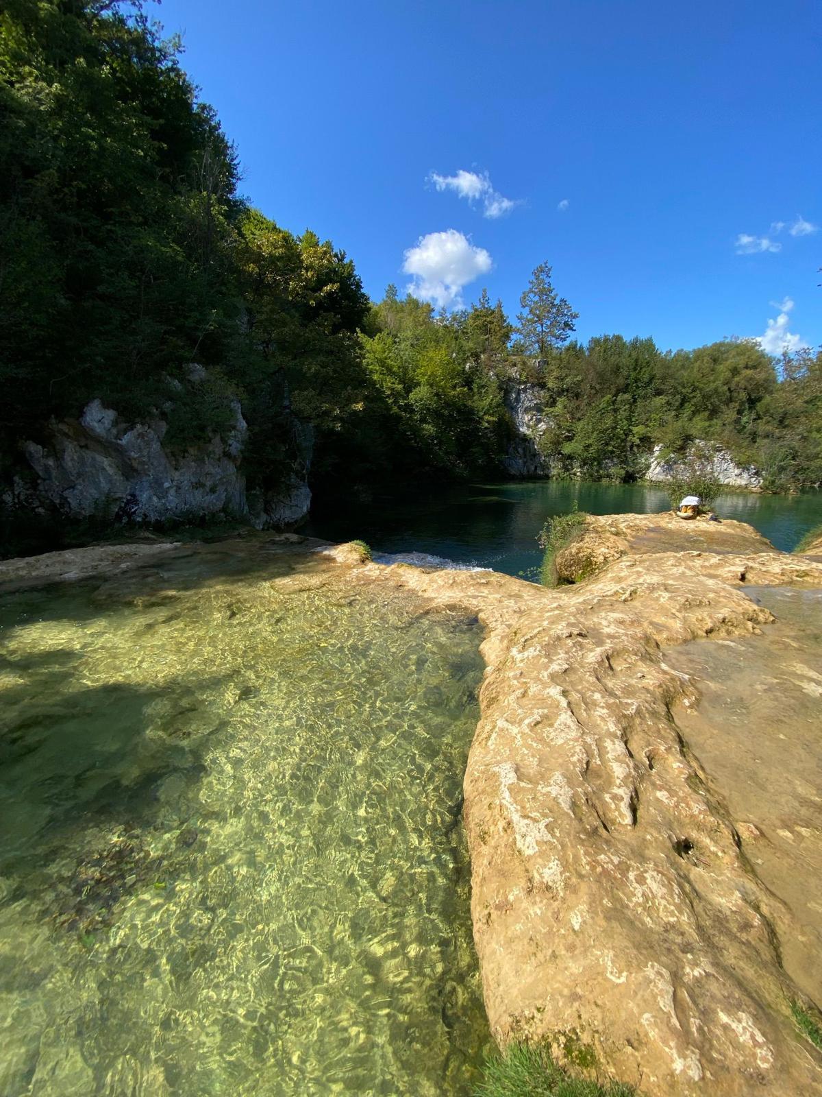 Kristalno čista rijeka s vapnenačkim stijenama i gustim zelenilom — fotografija okolice