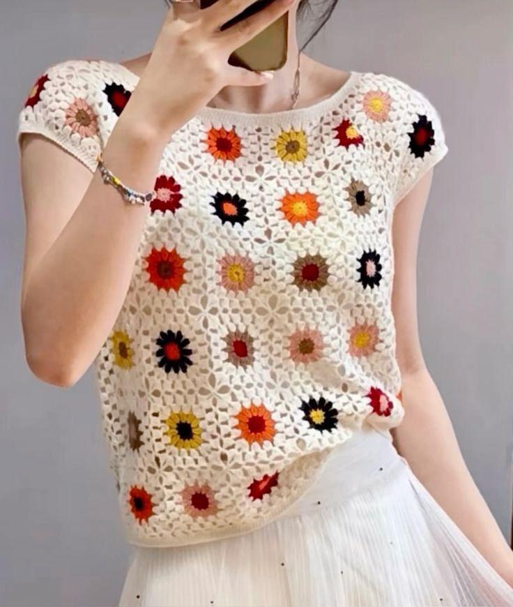 Close view of an ivory crochet top with colorful flower motifs.