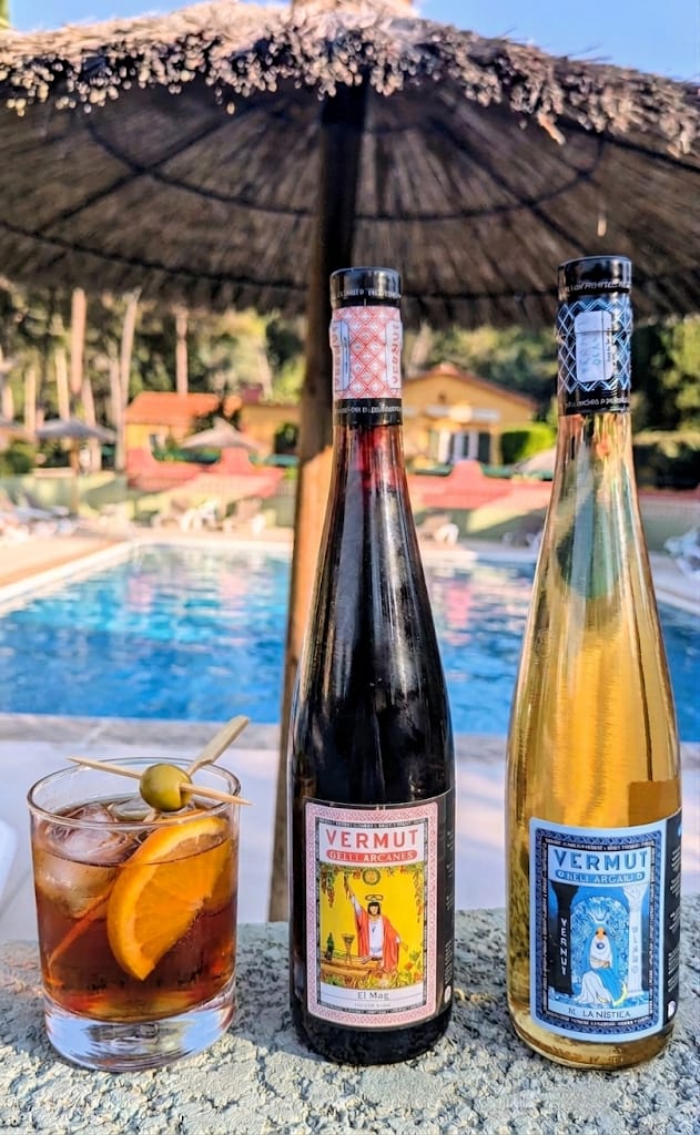 Ampolles de Vermut dels Arcans i una copa vora la piscina