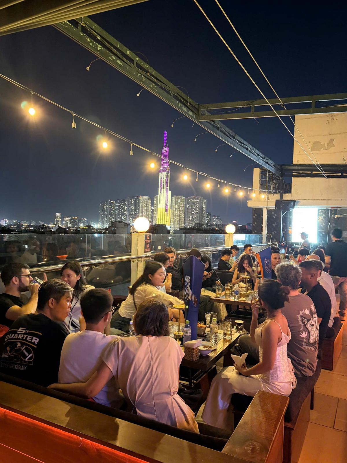 Busy rooftop bar beneath string lights at night