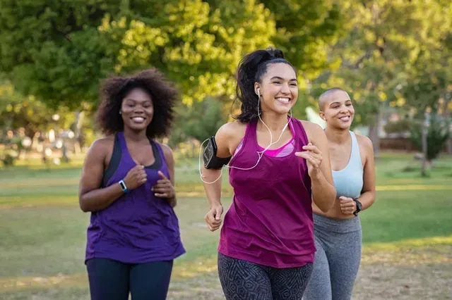 Three smiling women jogging together outdoors in a park after a medical weight loss program at Prime IV Flemington