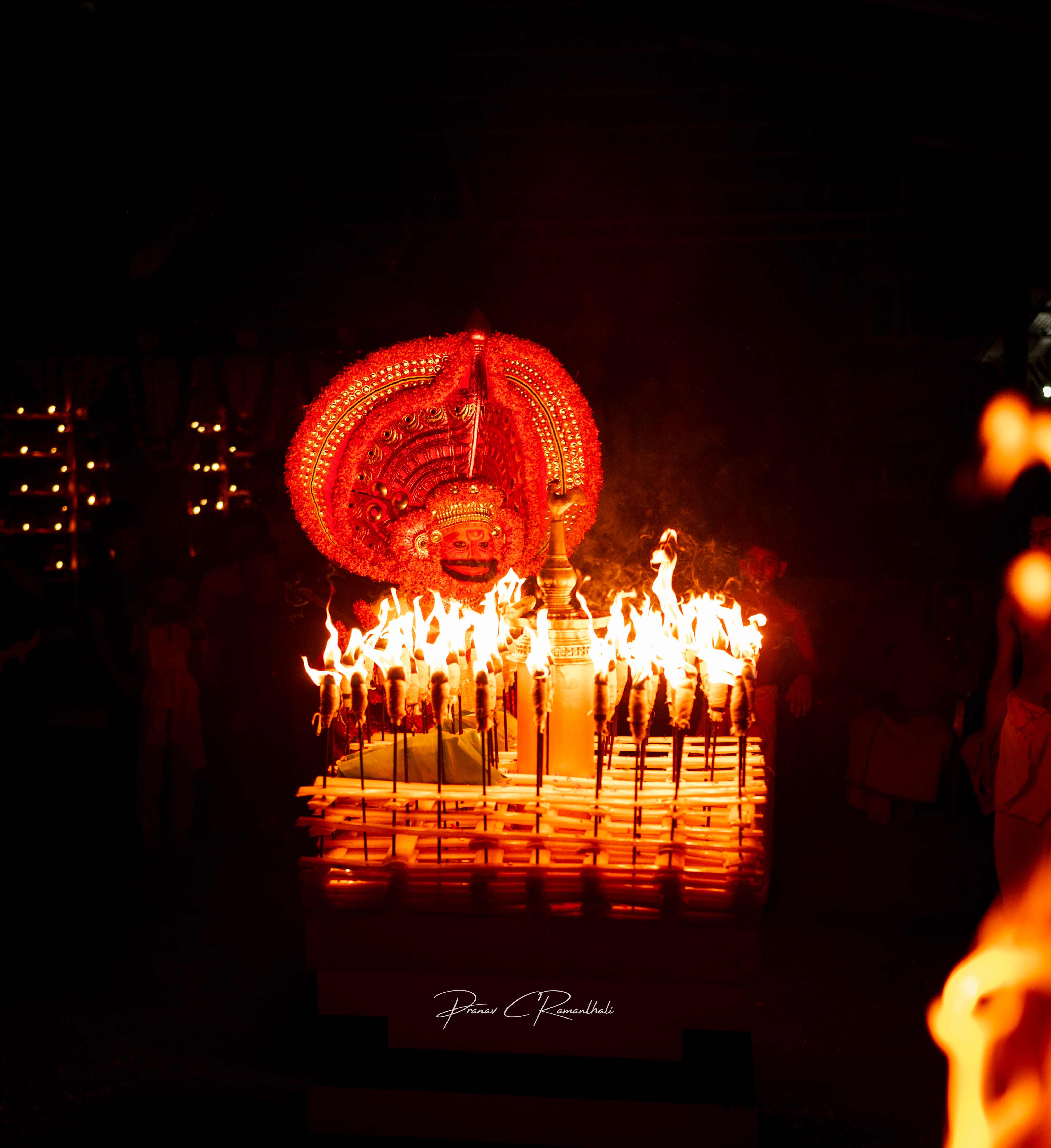 Theyyam performer with ceremonial fire torches in a traditional ritual performance