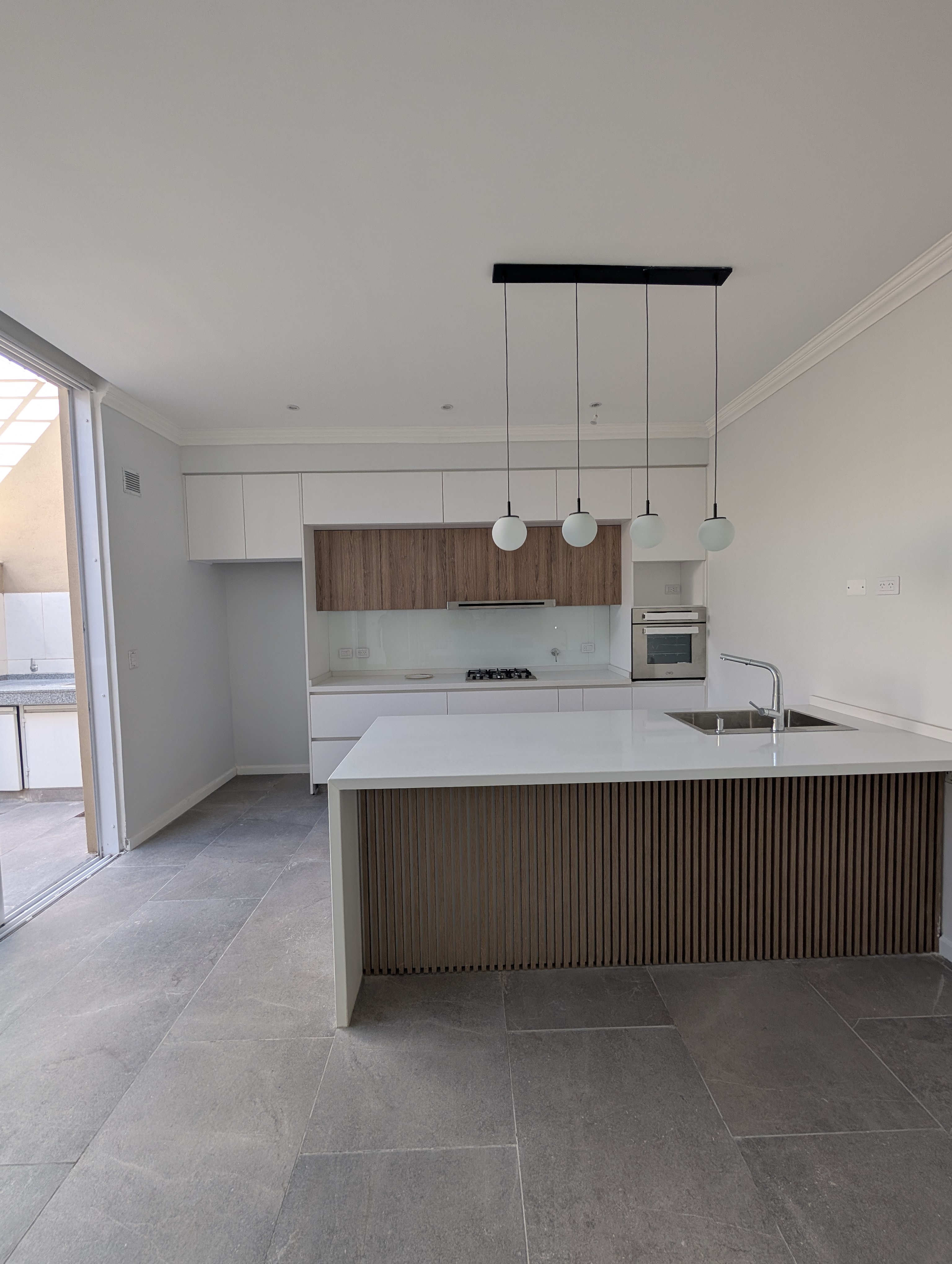 Cocina con isla de listones, alacenas de madera y piso de piedra gris