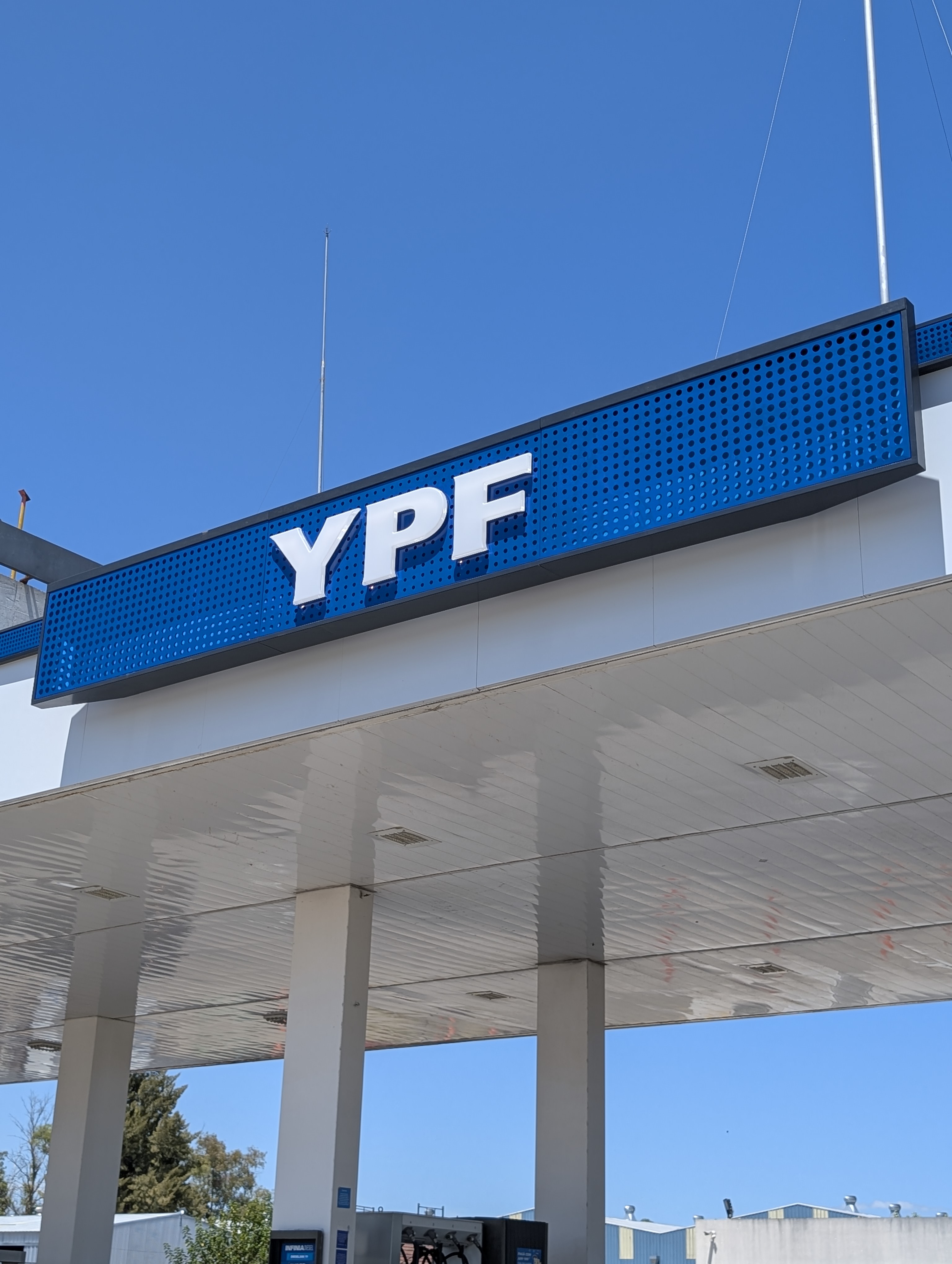 Detalle del cartel YPF sobre panel azul perforado