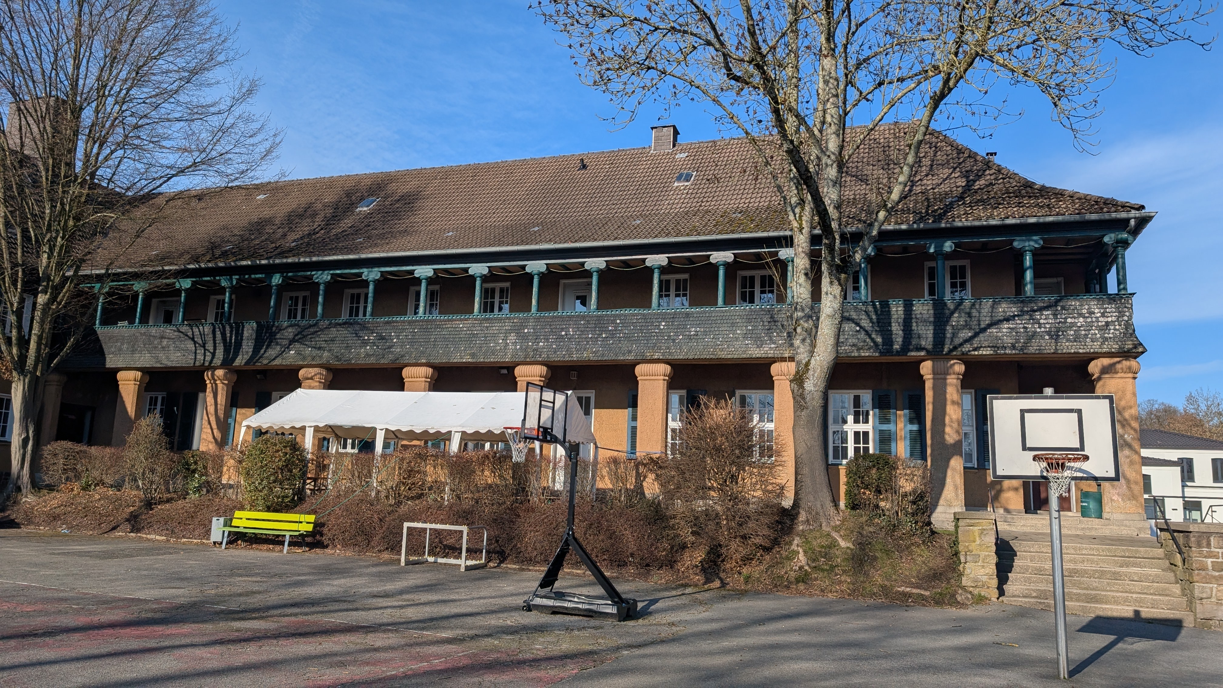 Seitenansicht mit grüner Veranda und Außenbereich mit Basketball-Korb