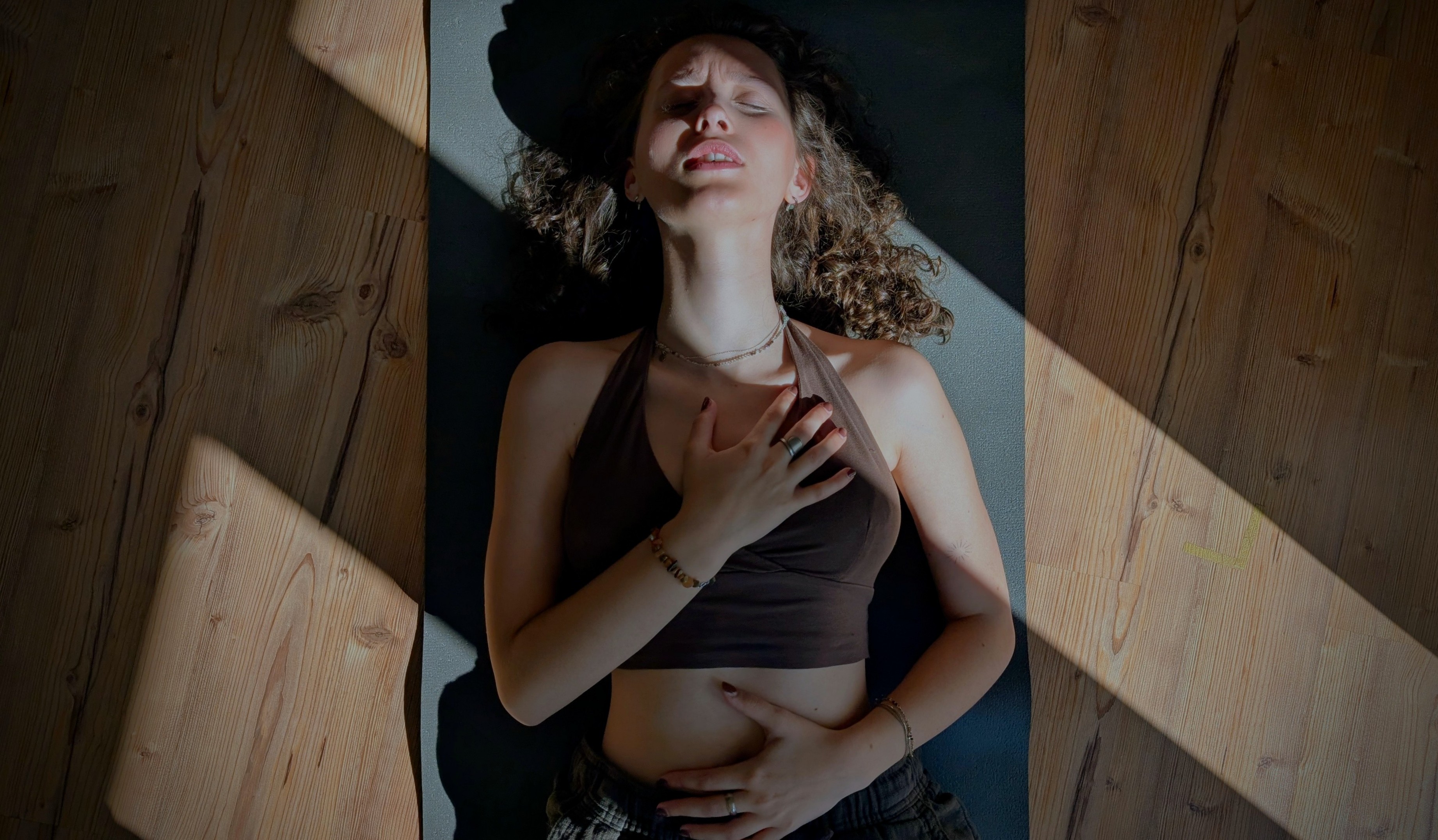 Woman lying on yoga mat with hands on chest, dramatic light beams