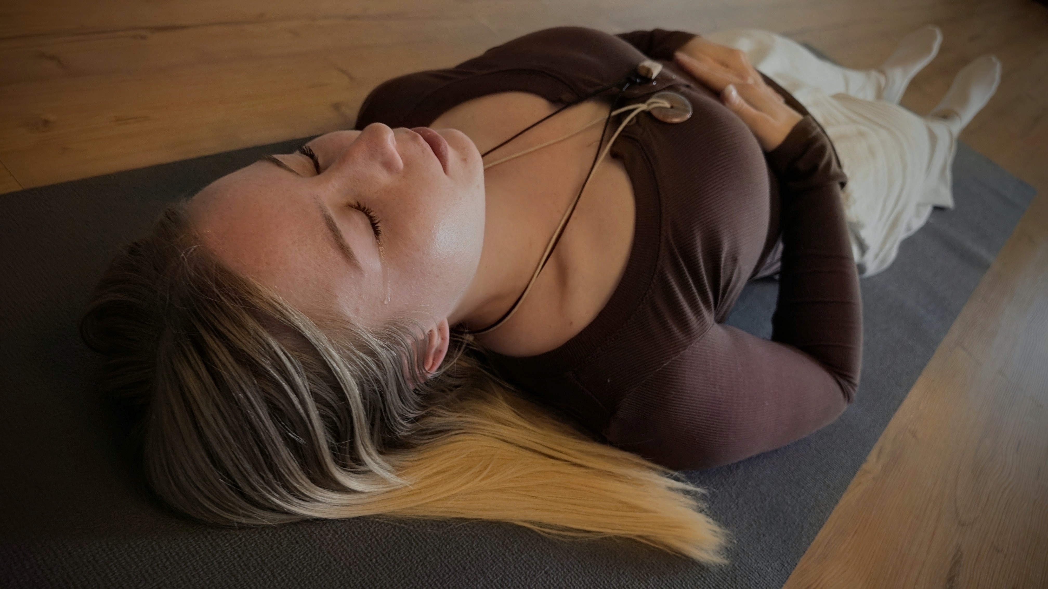 Woman lying on mat with tear, dramatic light beams