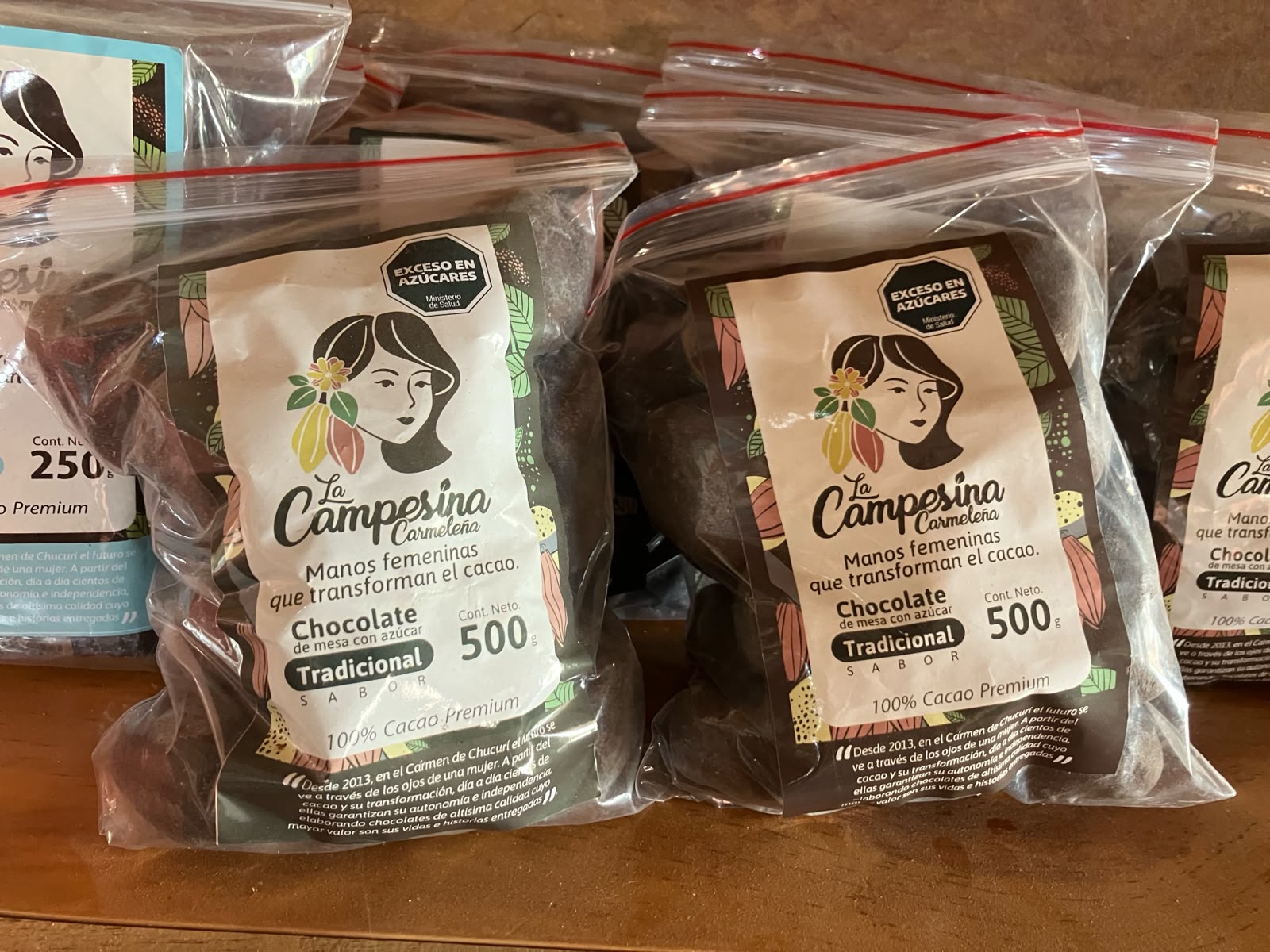 Bolsas de chocolate de mesa La Campesina Carmeleña, 100% cacao premium, sobre una mesa de madera