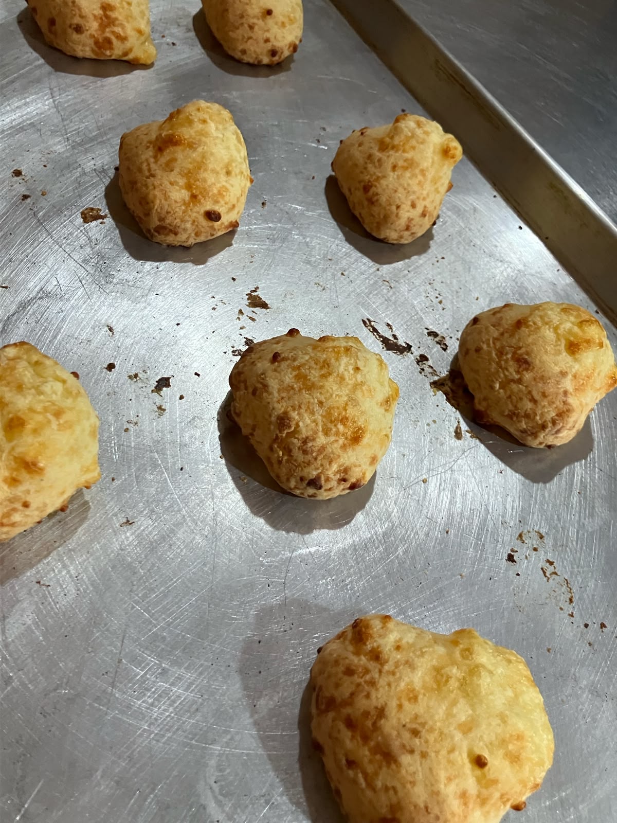 Pandebonos recién horneados sobre bandeja de aluminio, dorados y esponjosos
