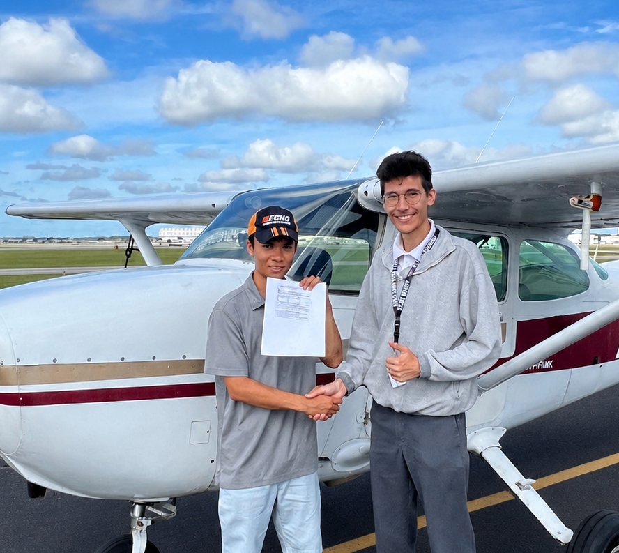 Student and instructor celebrating checkride pass with handshake in front of Cessna aircraft