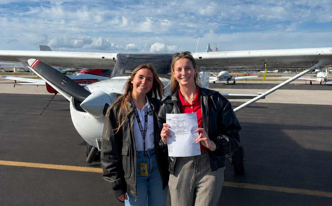 Instructor and student celebrating checkride pass together in front of training aircraft
