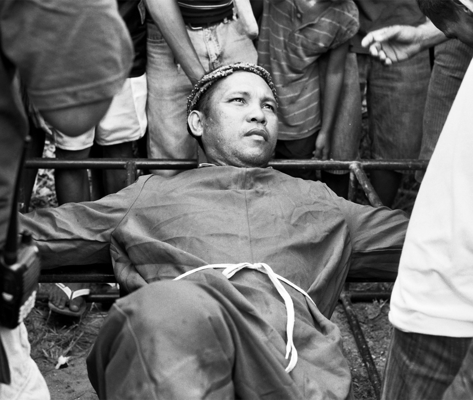 Man wearing decorative wreath surrounded by crowd at cultural or ceremonial gathering