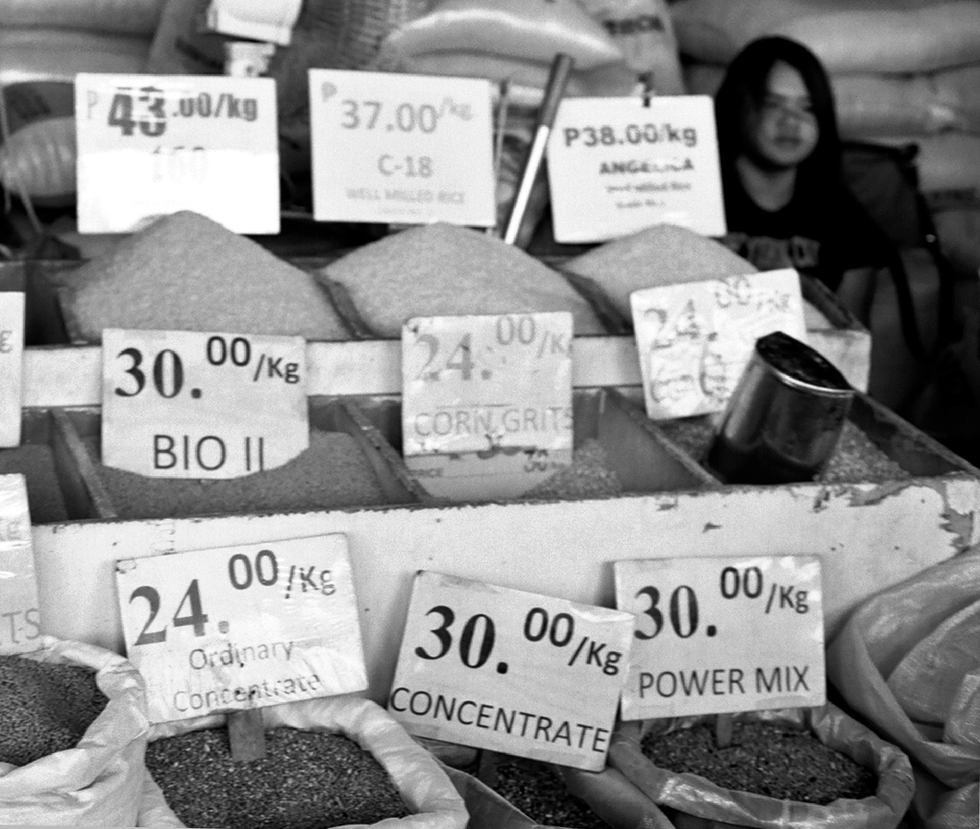 Market vendor display with various bagged grains and food products with price labels