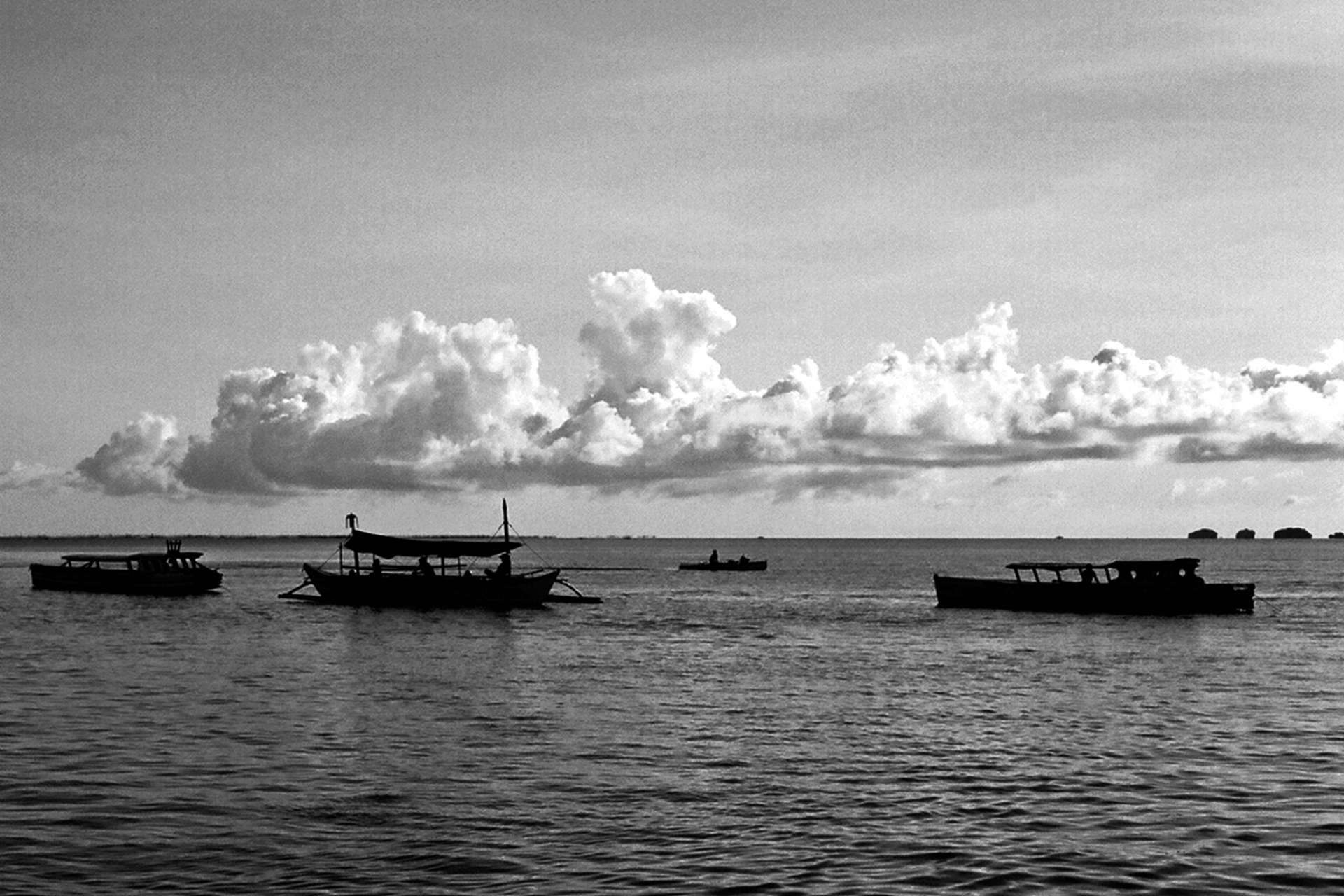 Fishing boats moored in calm water with dramatic cumulus clouds filling sky