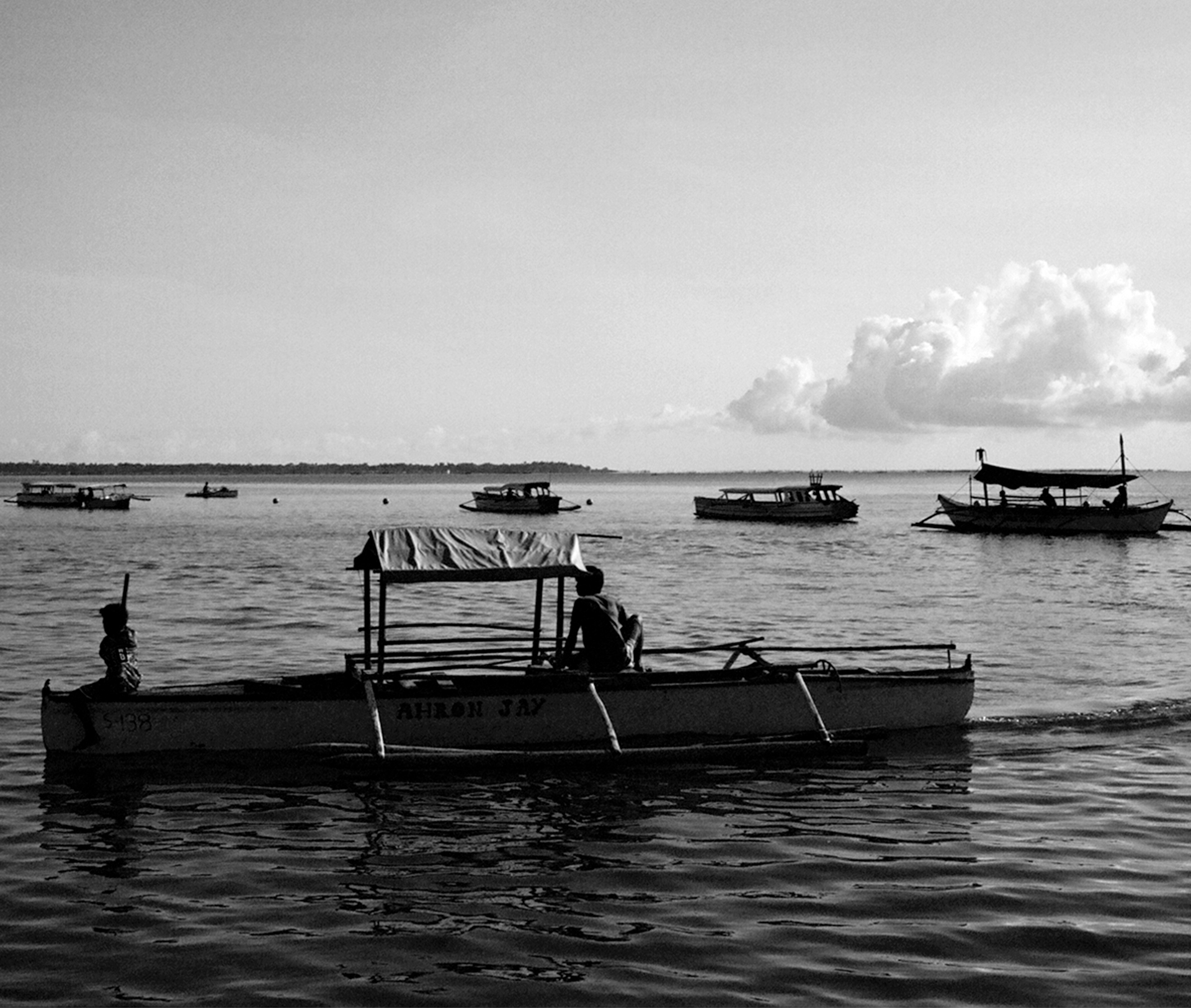 Traditional fishing boats moored in calm shallow water with dramatic cloud formations