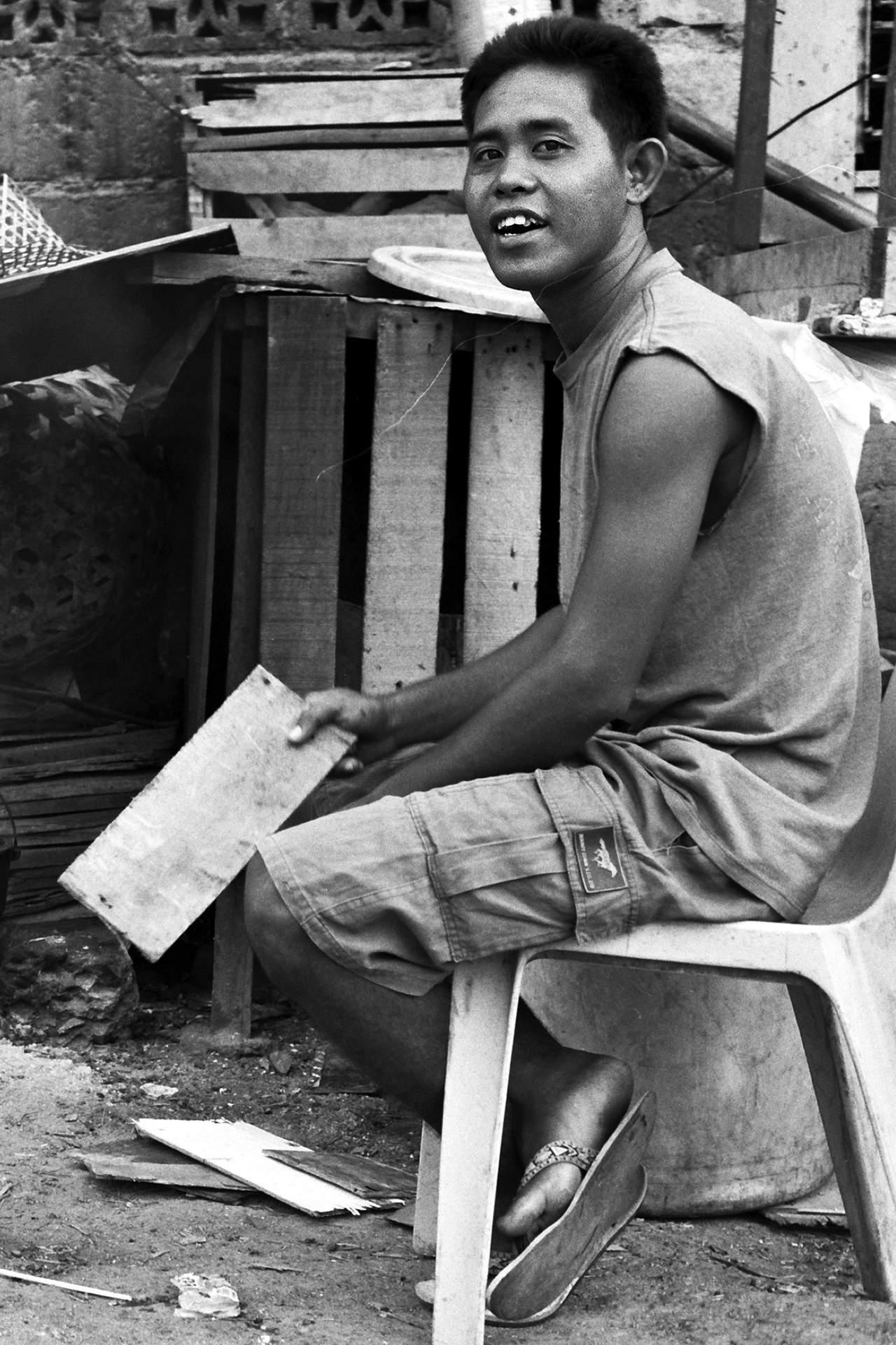 Young man working with wood materials smiling at camera near wooden structures