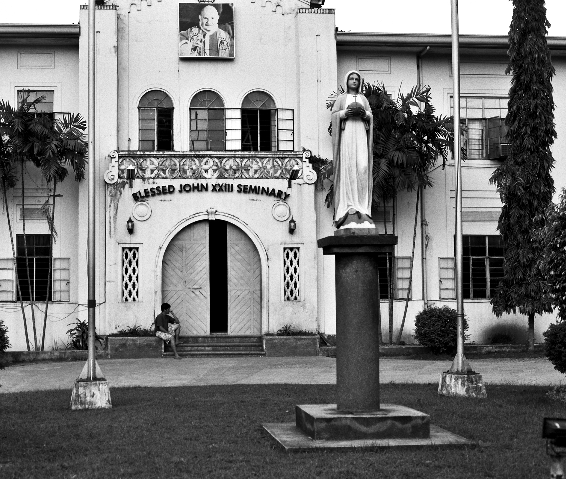 Religious seminary building with Jesus statue on pedestal and colonial architecture