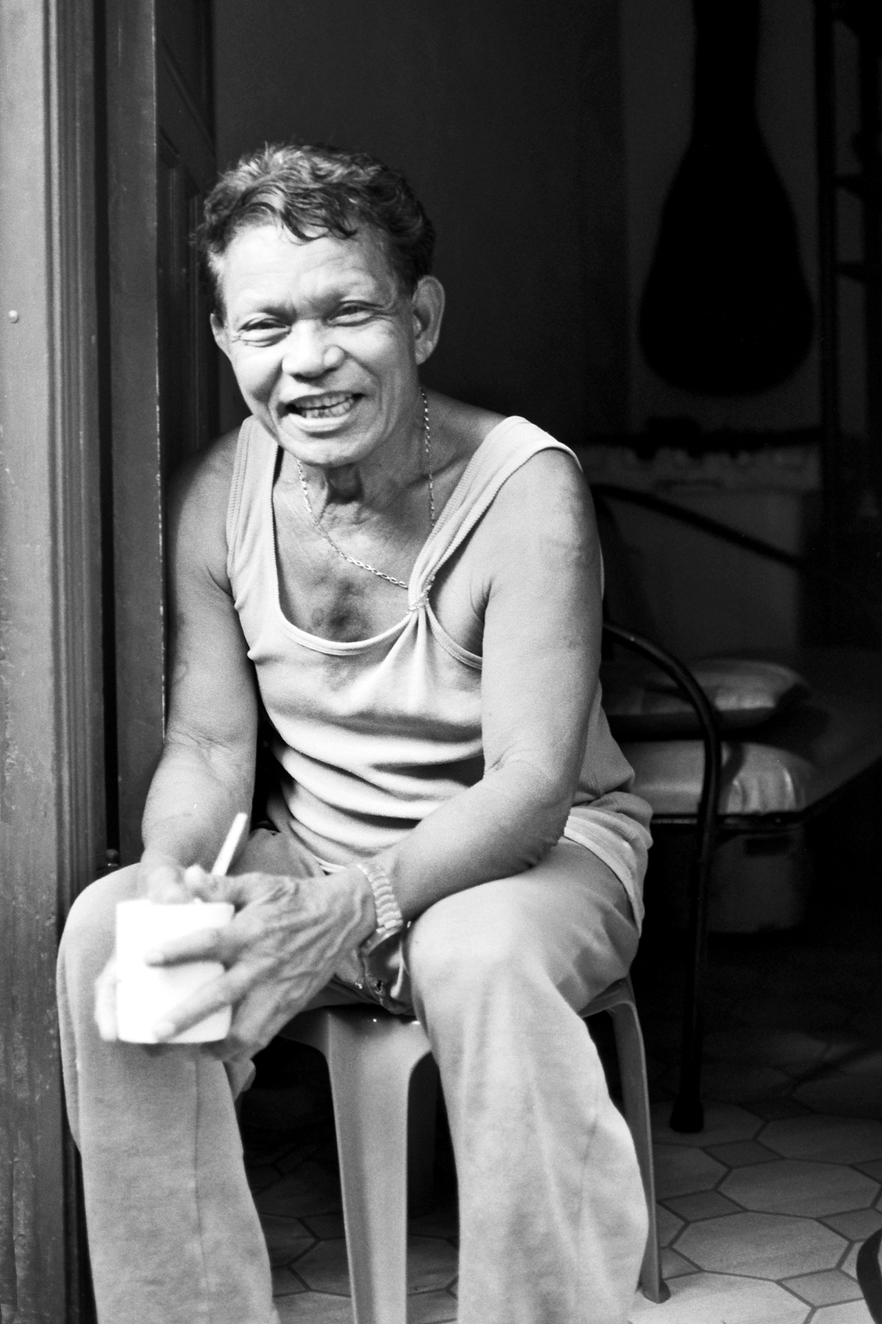 Portrait of elderly man with warm smile sitting in doorway wearing casual clothing