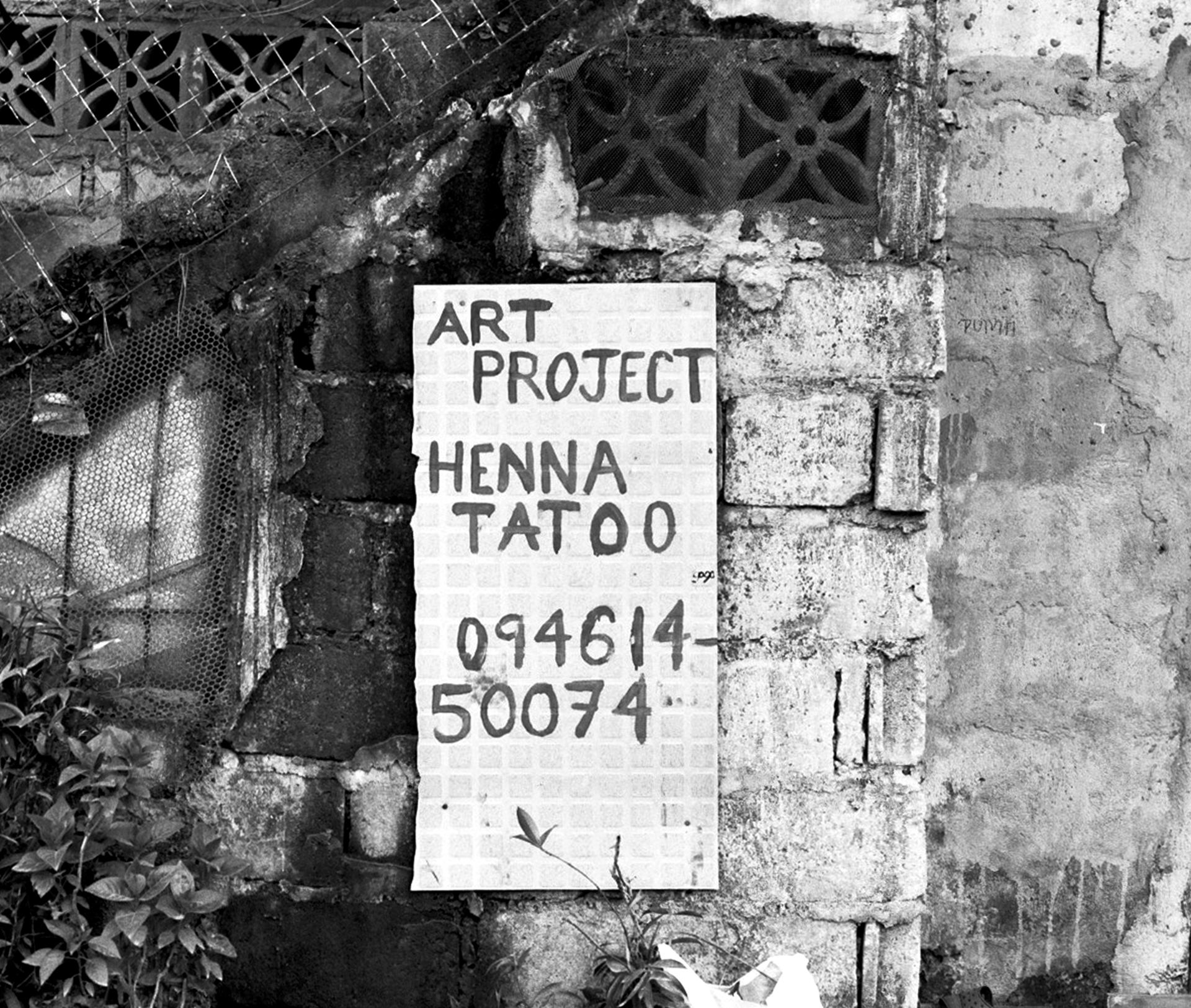 Handwritten Art Project Henna Tattoo sign on weathered brick wall