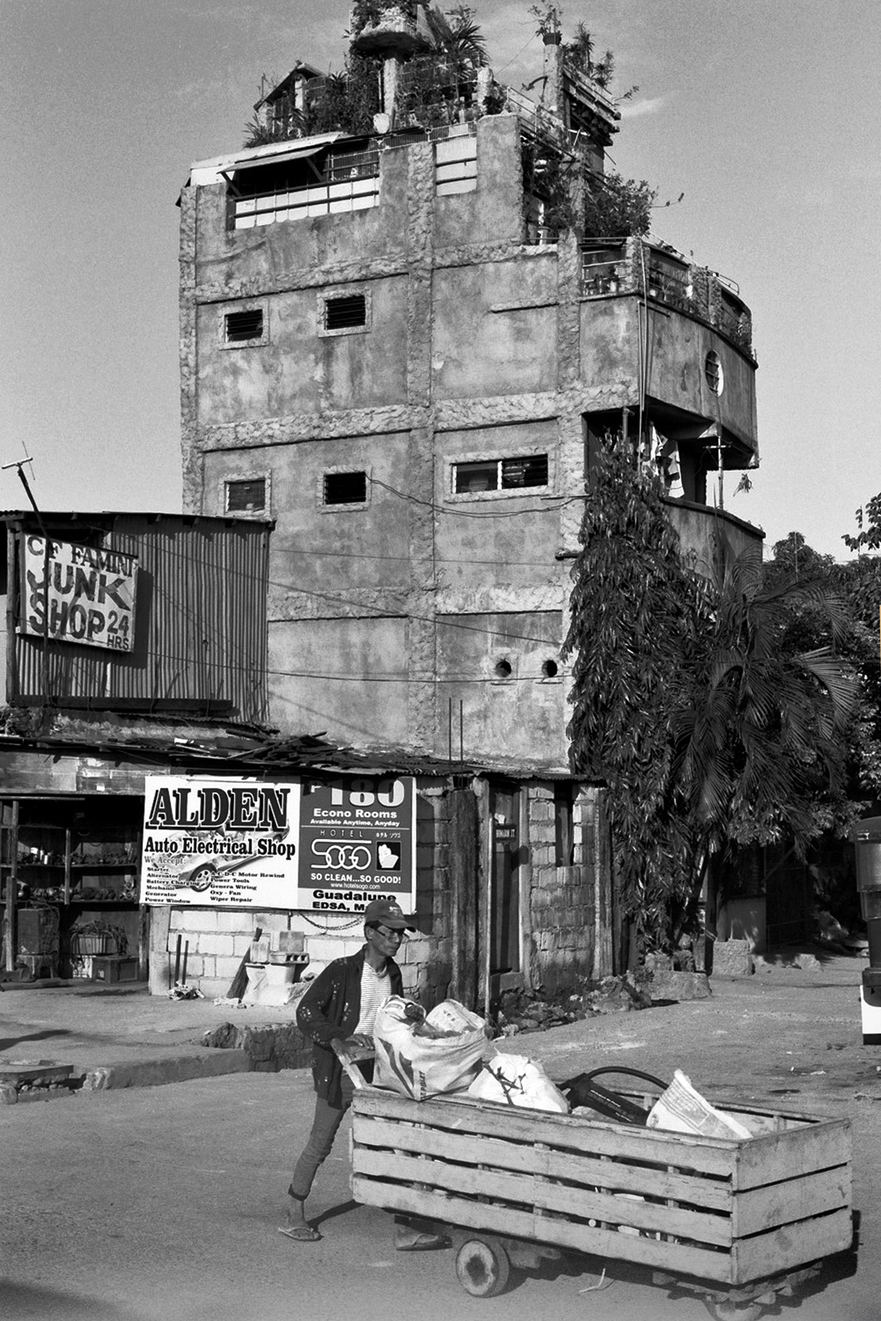 Man with cart in front of multi-story building with shops and signage