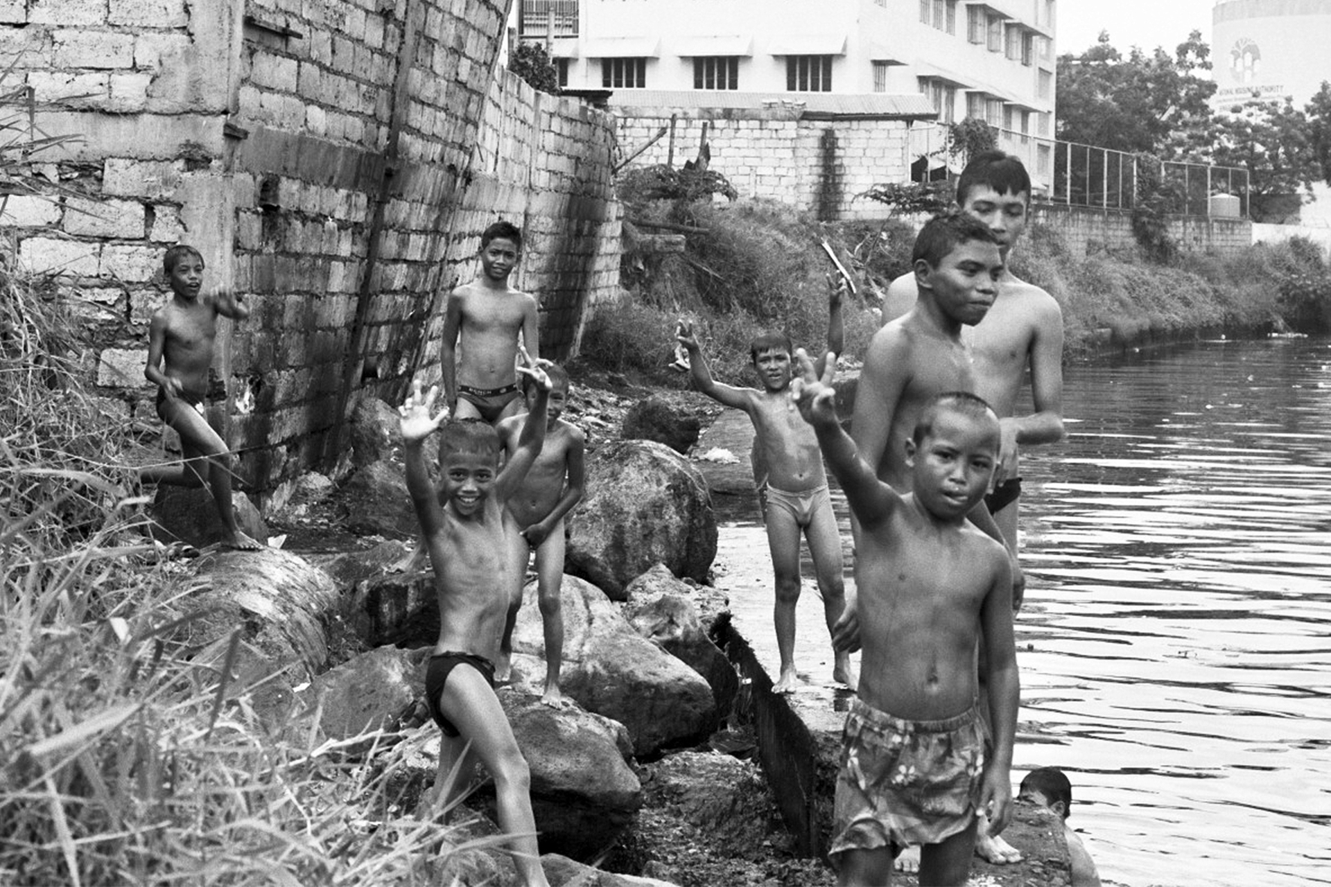 Group of children and young people at waterside near stone walls and buildings