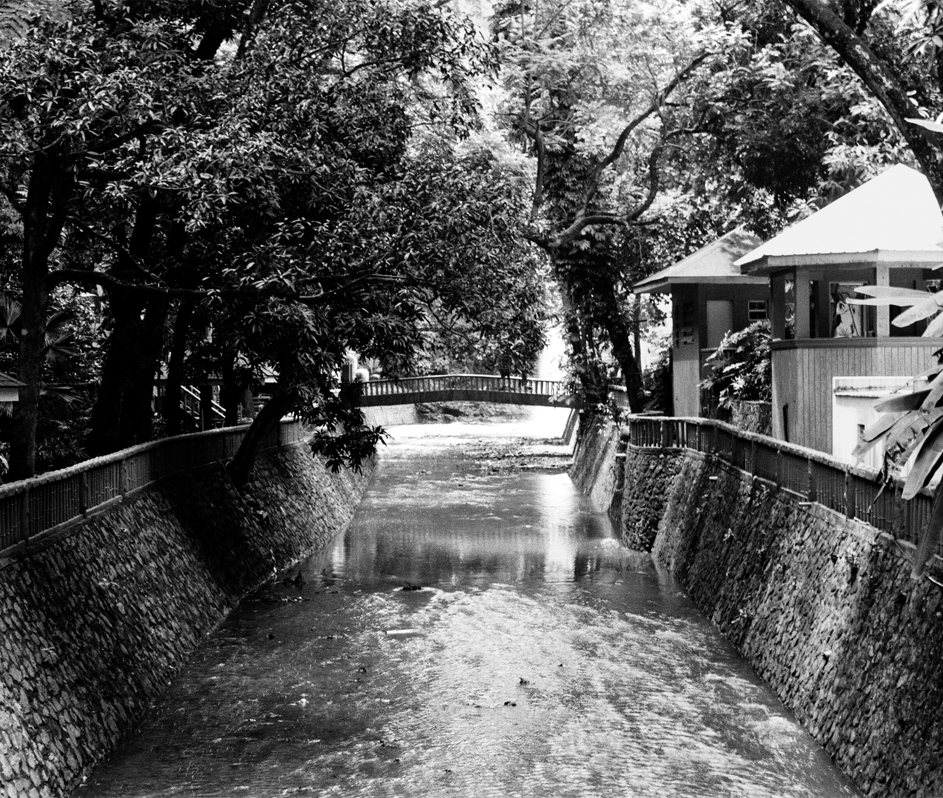 Black and white waterway with stone walls traditional building water reflections and vegetation