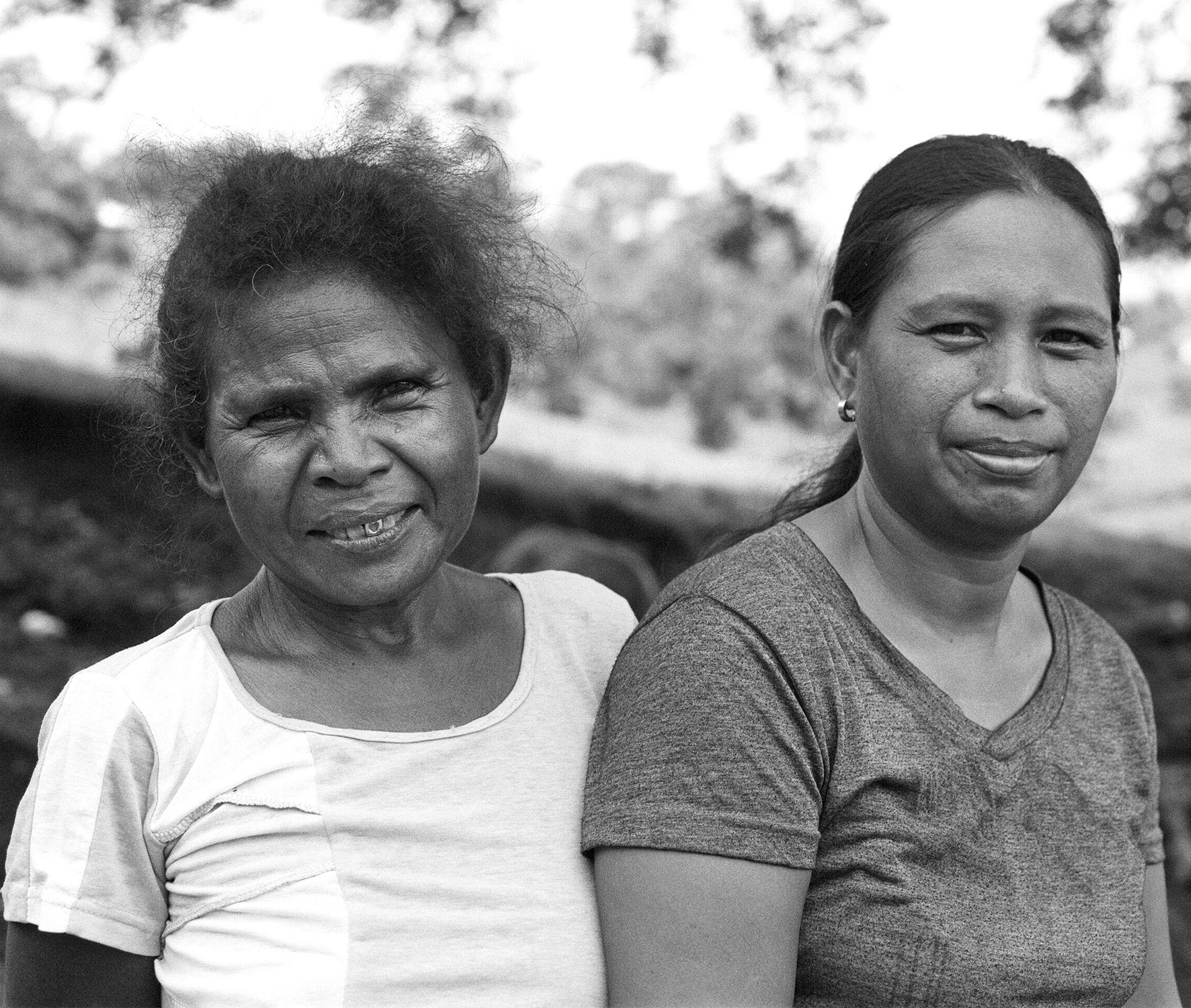 Black and white portrait of two women smiling together outdoors with buildings in background