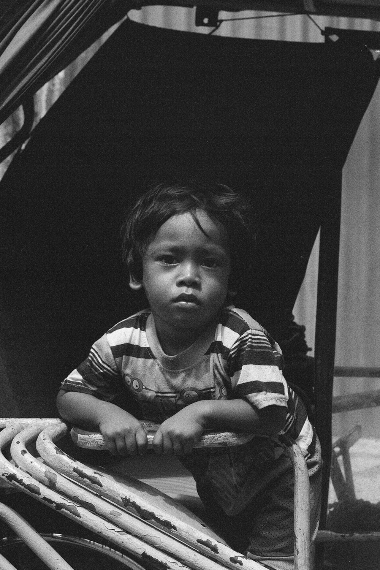 Black and white portrait of young boy in traditional woven boat with serious concentrated expression