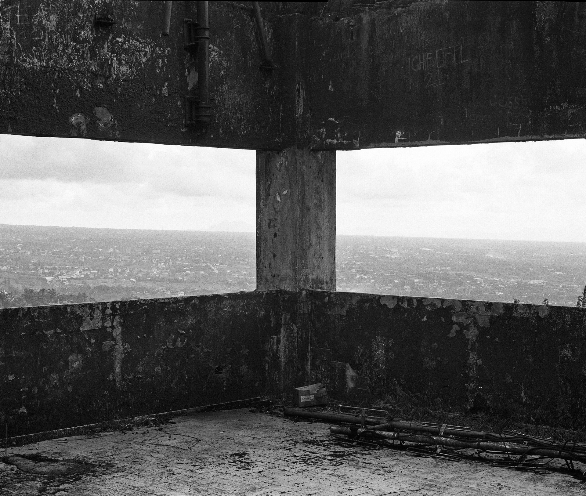 Black and white ruined concrete structure with opening framing distant landscape