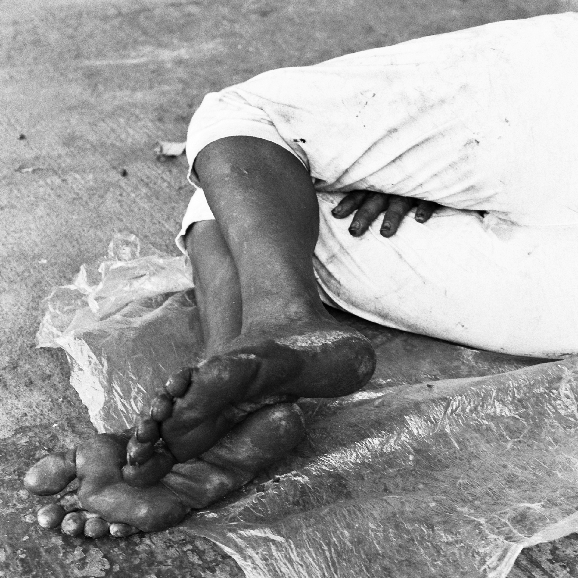 Black and white intimate detail of person in white cloth with hands and feet