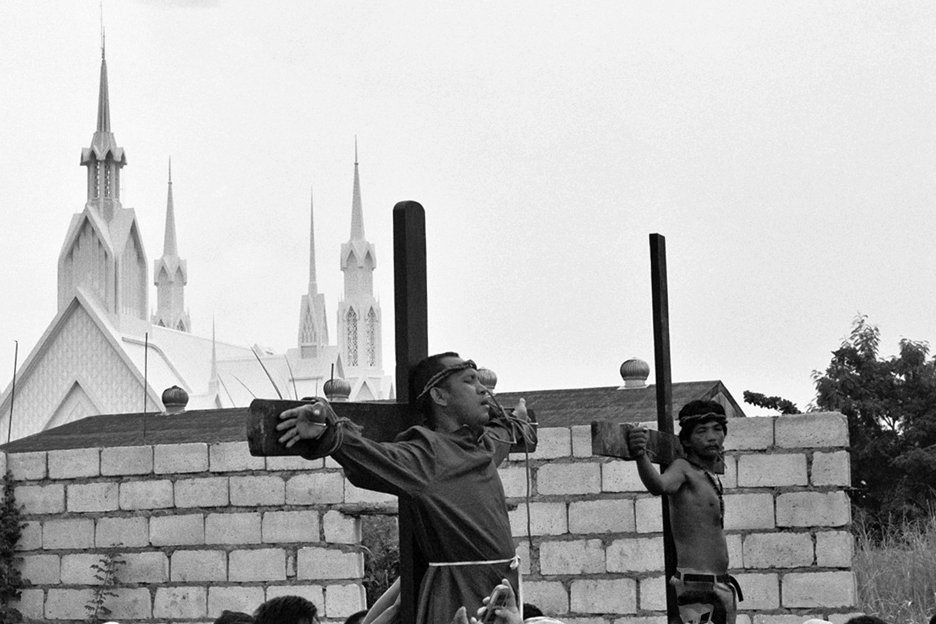 Black and white men working with wooden cross construction materials against church towers