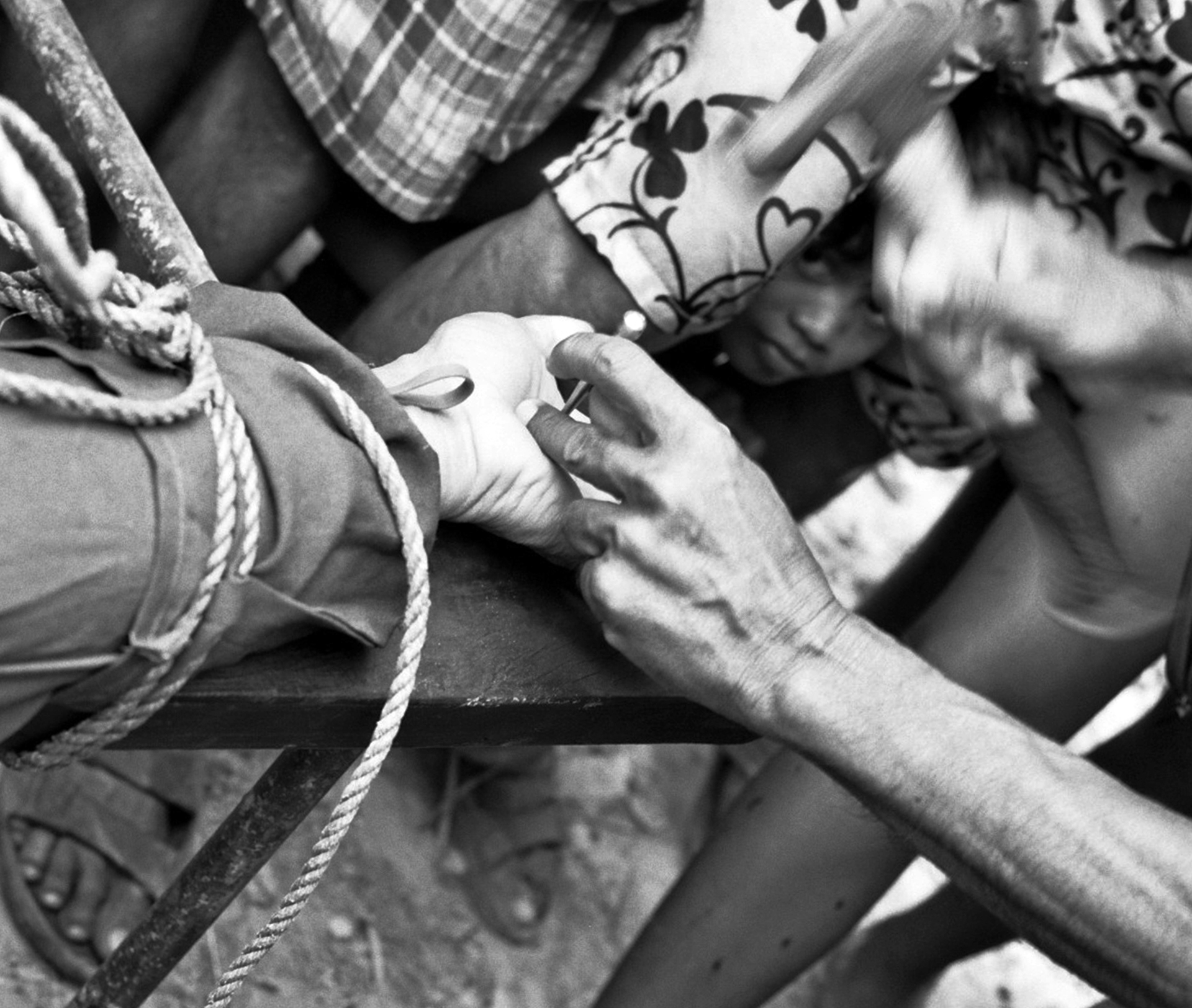 Black and white close-up of multiple hands working with rope and maritime rigging