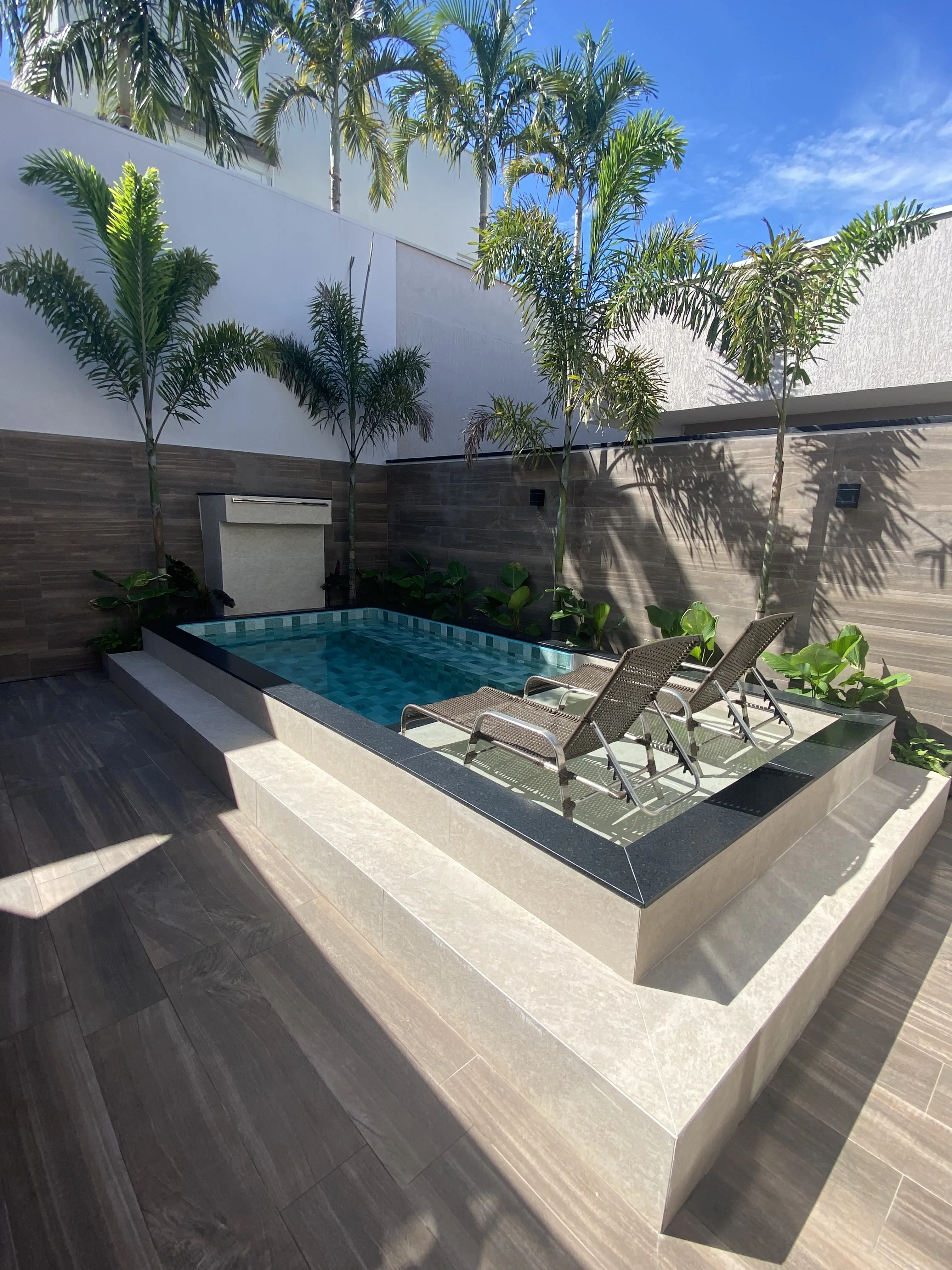Piscina moderna com deck em madeira e paisagismo tropical