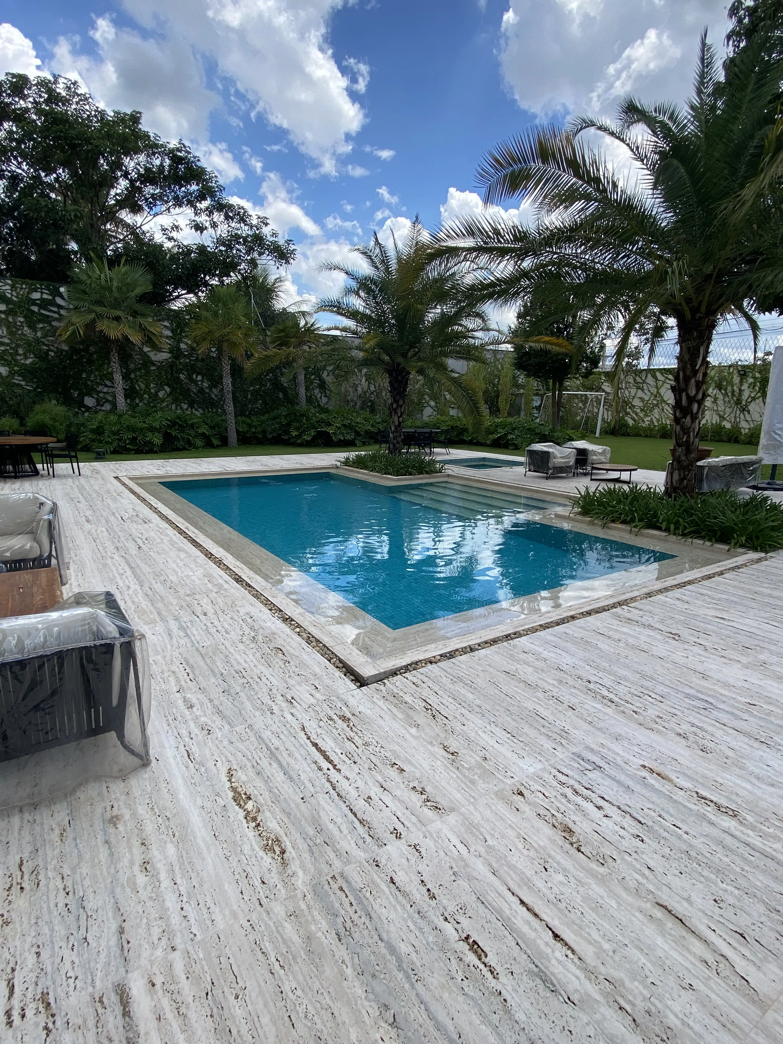 Piscina grande com spa integrado e paisagismo exuberante