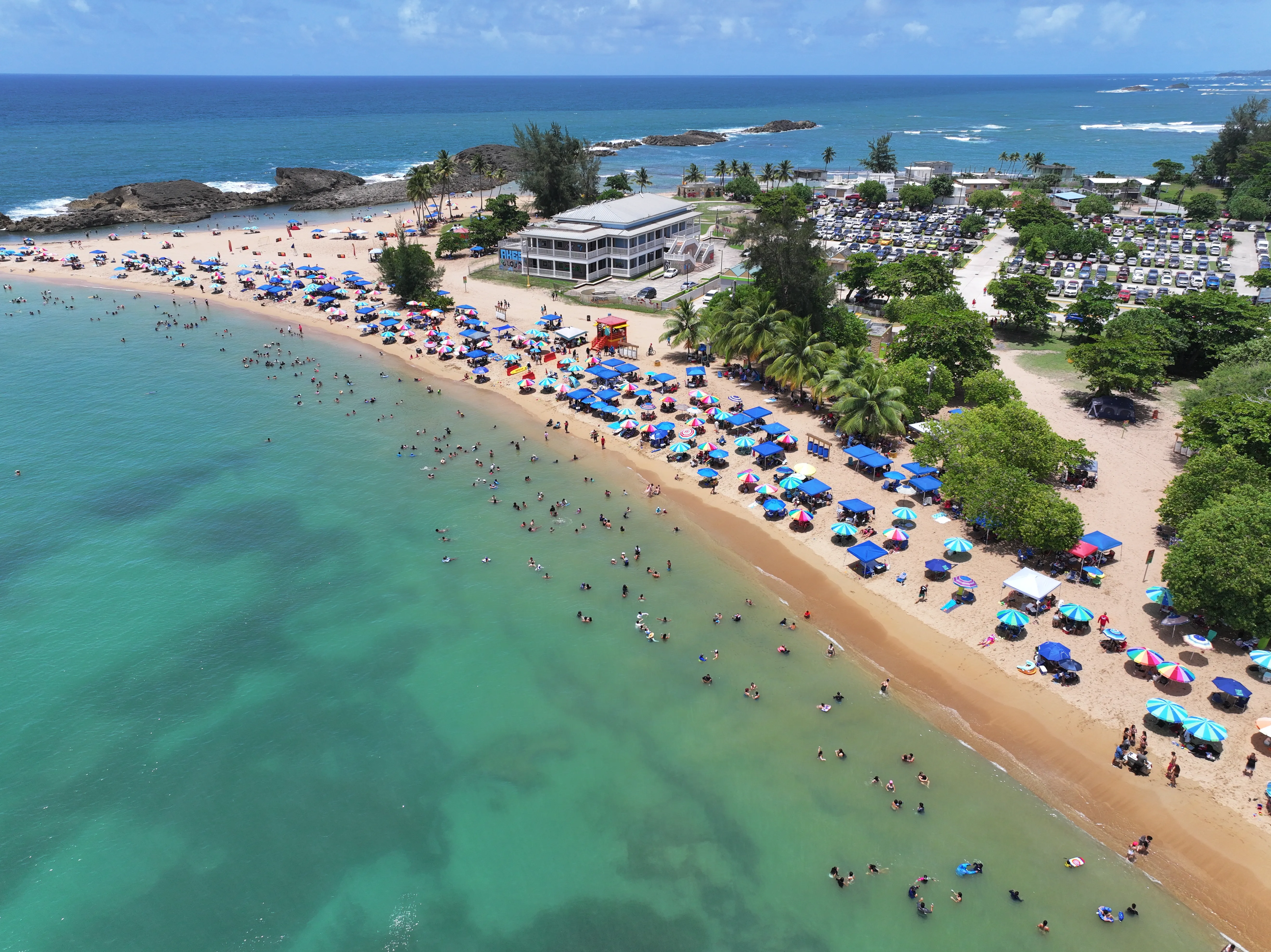 Aerial view of Playa Puerto Nuevo with turquoise water and colorful beach umbrellas