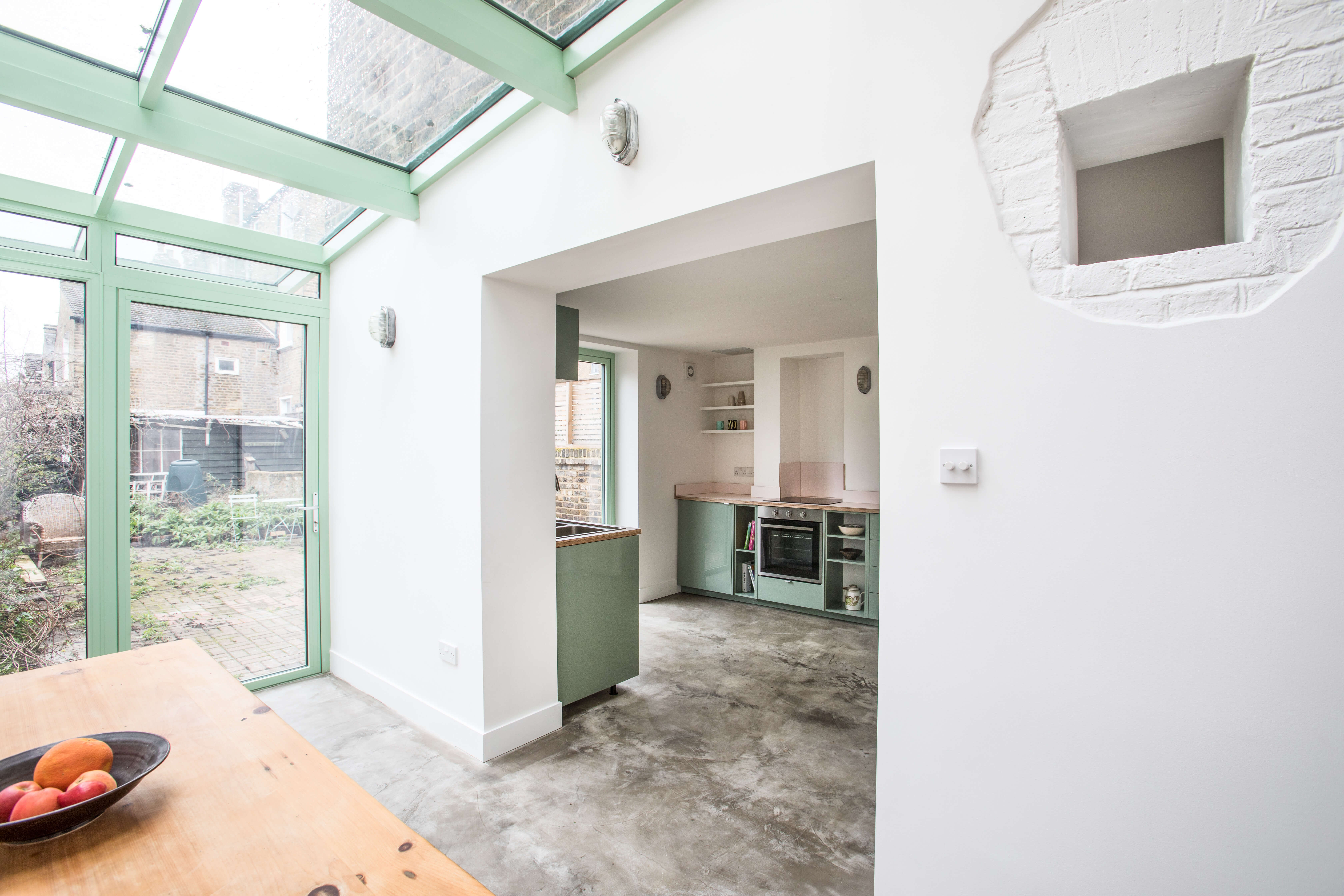 View from conservatory into kitchen showing mint green cabinetry and polished concrete flooring