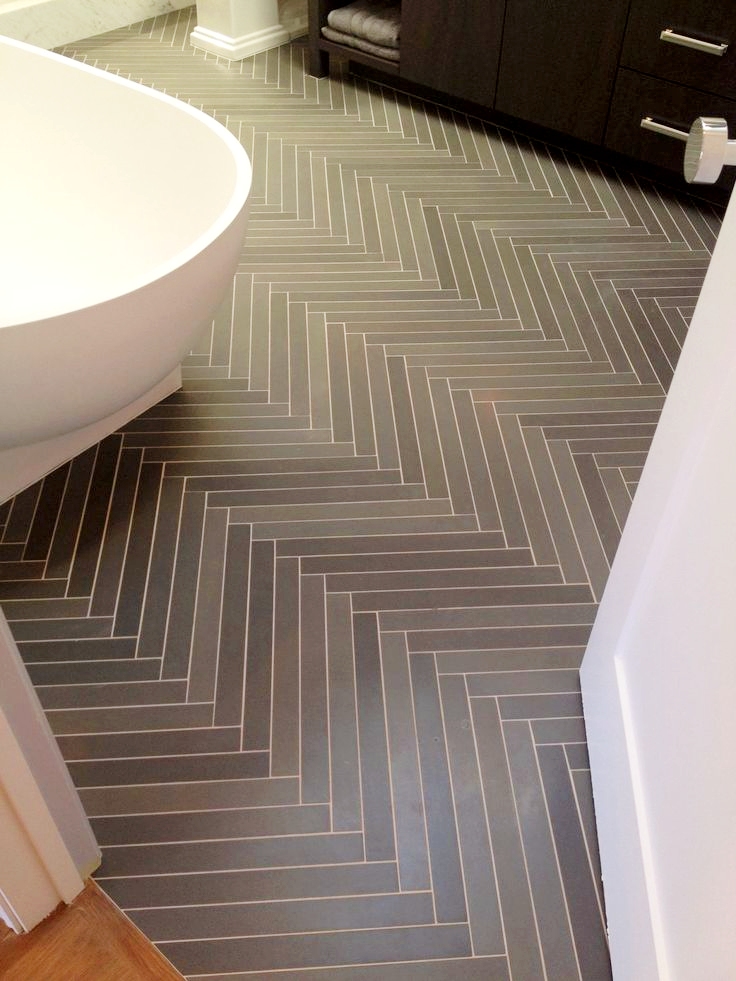 Large format herringbone bathroom floor with grey and light wood-look porcelain tiles